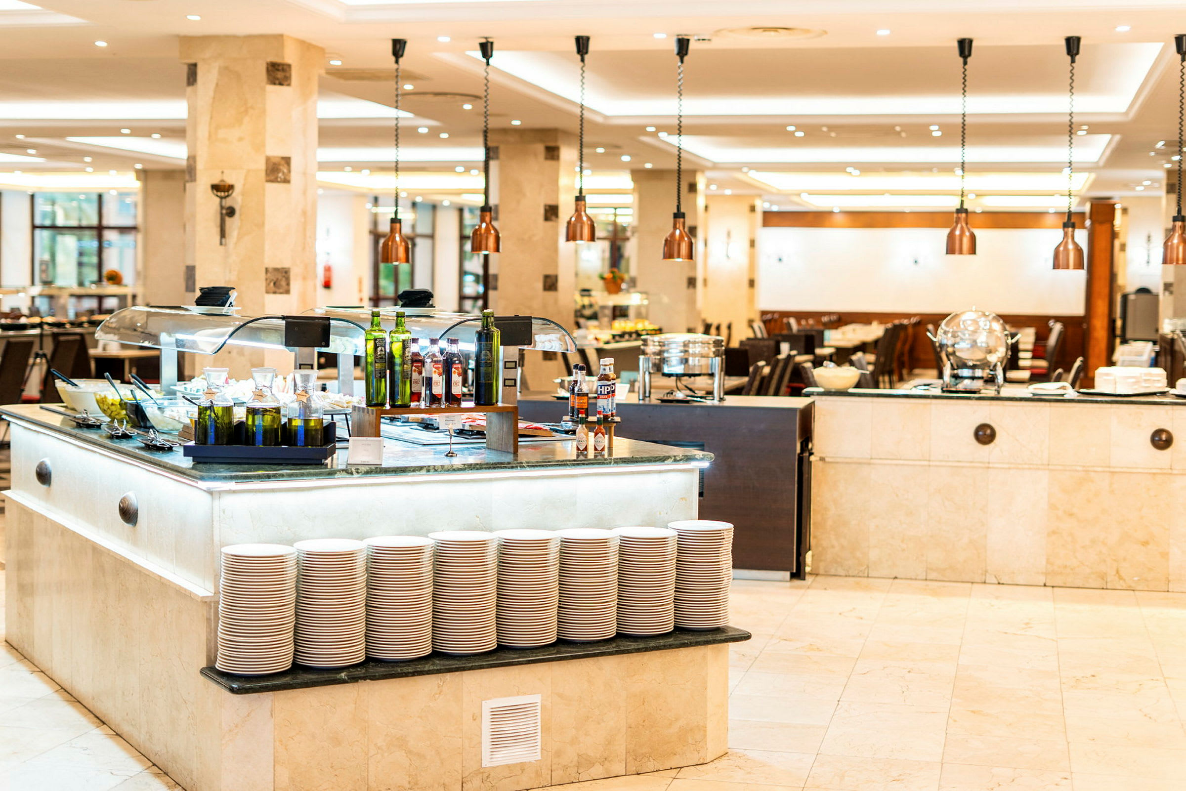 Bufféområde i en restaurang med olika mattråg, oljeflaskor och tallrikar. (AI-genererad text)
