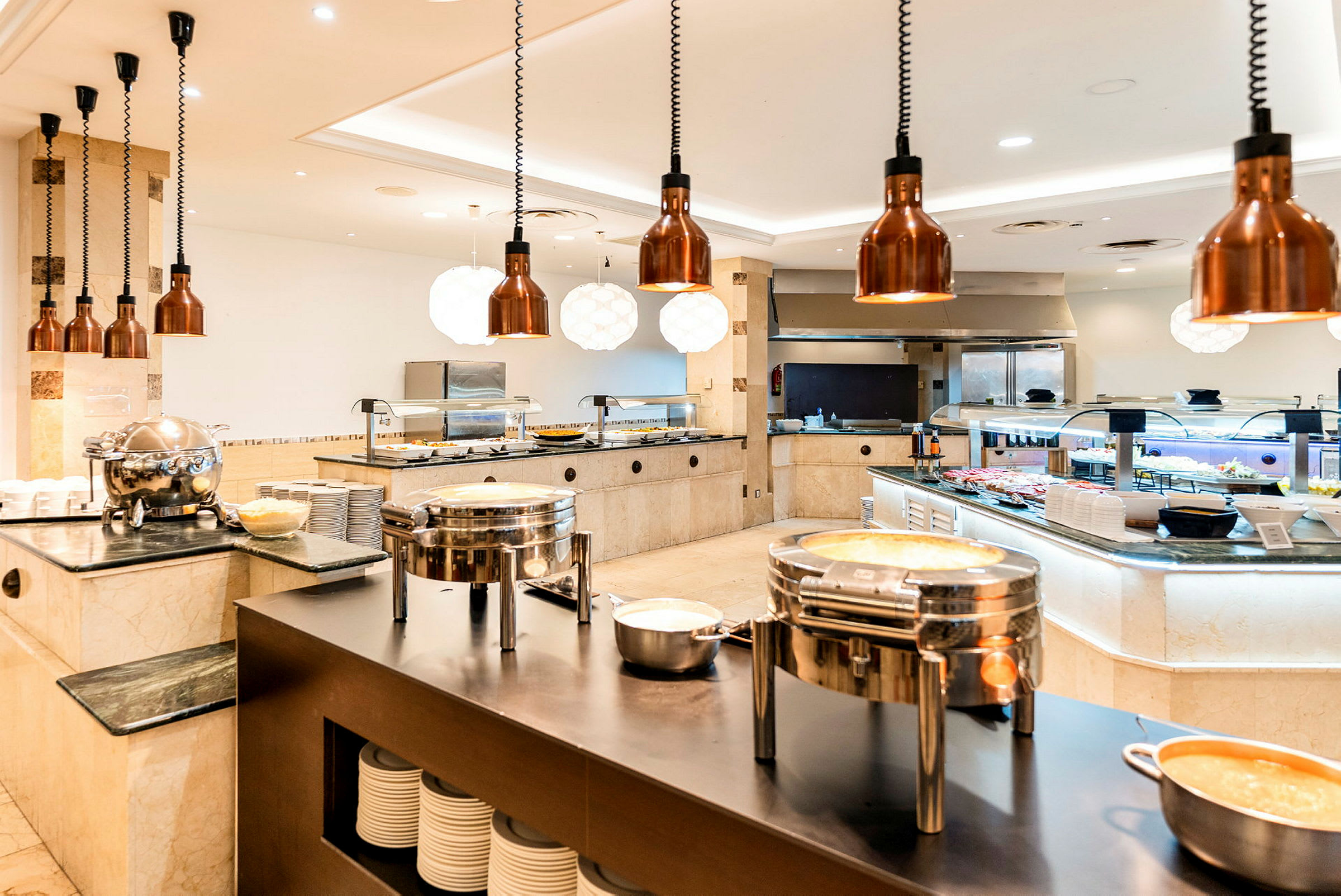 En bufférestaurang med serveringsstationer och mat uppställd på disk. (AI-genererad text)