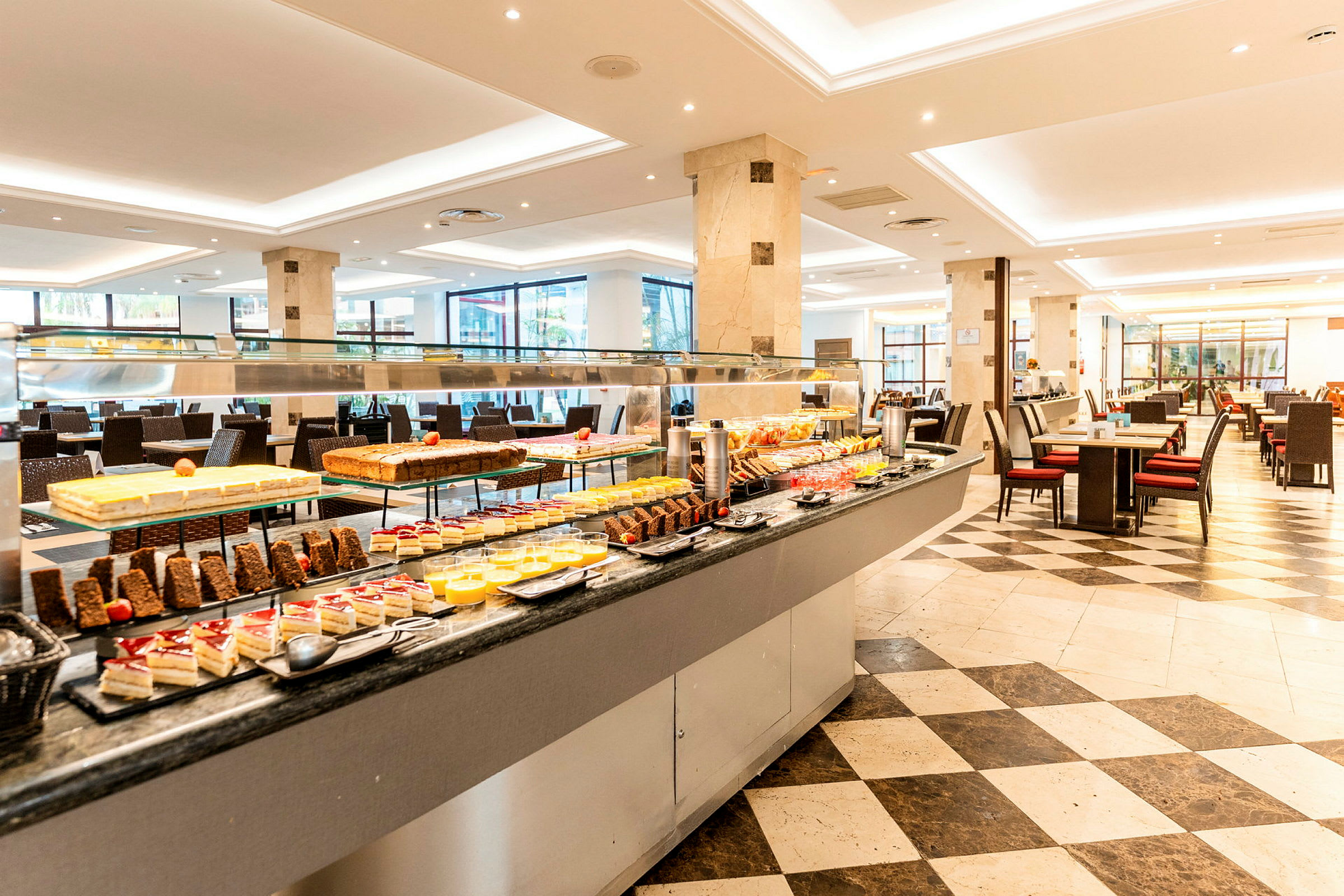 En buffé i en restaurang med assorterade desserter och mat, omgivande sittplatser. (AI-genererad text)