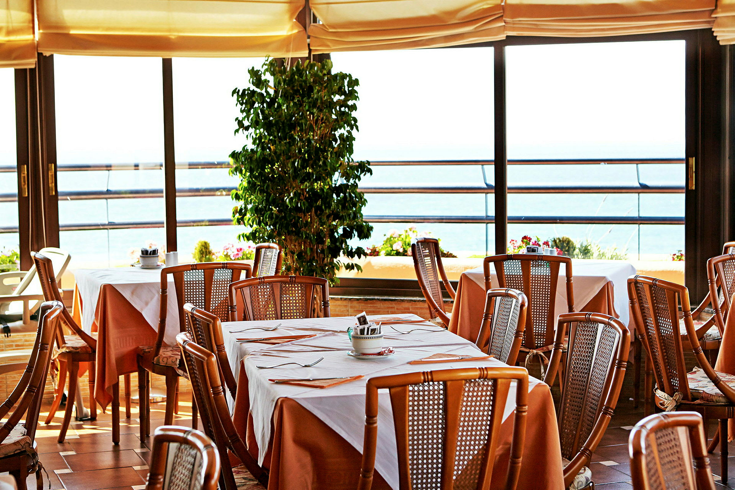 Restaurang med dukade bord och utsikt mot havet. (AI-genererad text)