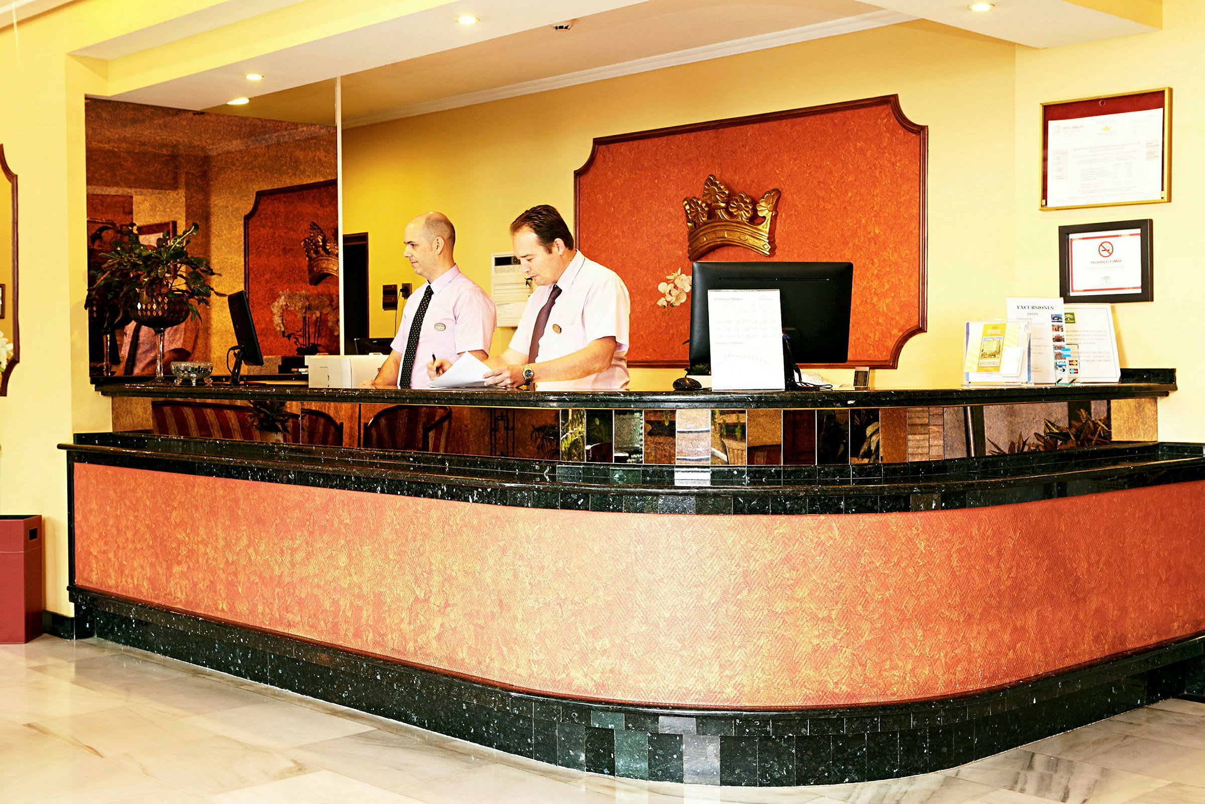 Reception i en hotelllobby med en svart och orange färgsättning och dekorationer. (AI-genererad text)
