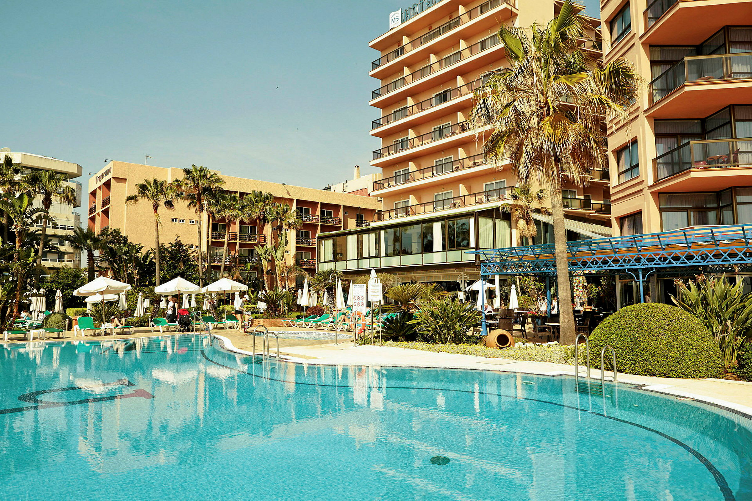Ett hotell med en pool och palmer. (AI-genererad text)