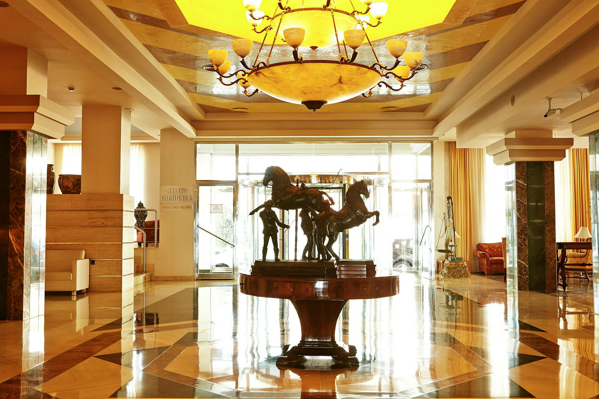 En ljus hotellobby med ett centralt bord som har en skulptur föreställande hästar. (AI-genererad text)