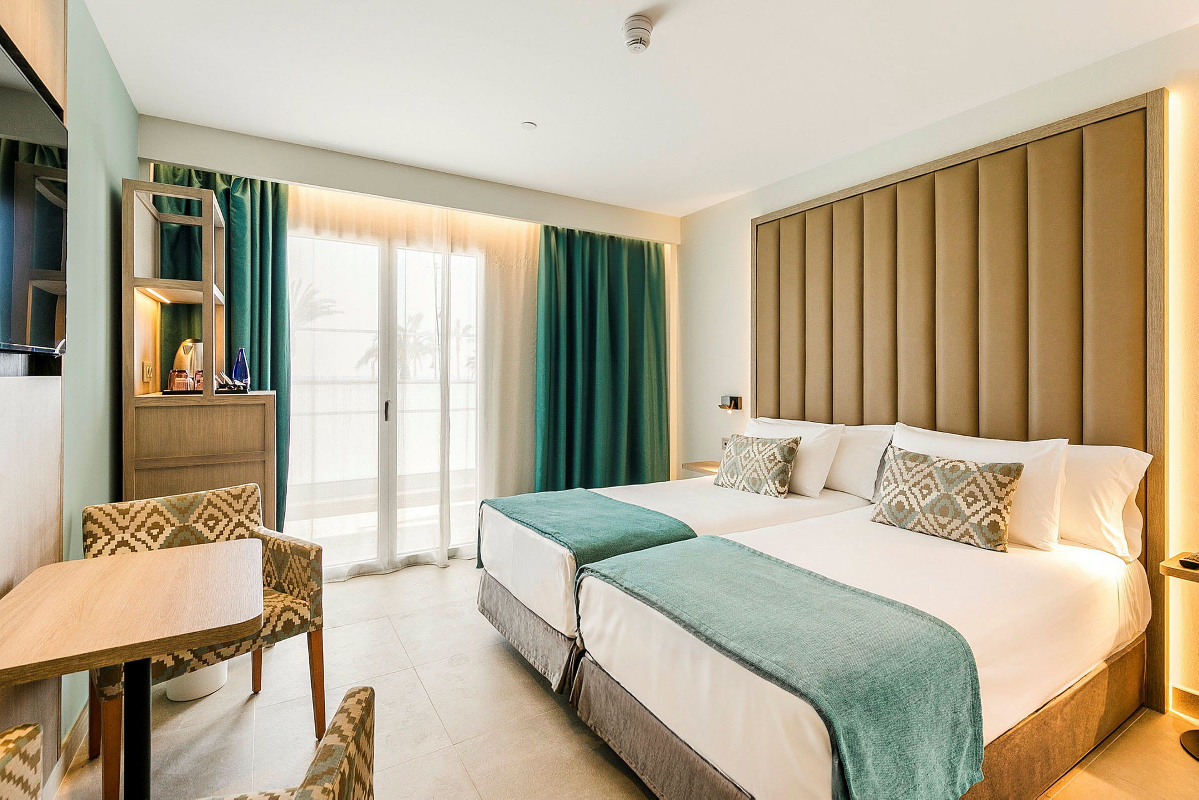 Hotellrum med två enkelsängar och sittgrupp. (AI-genererad text)