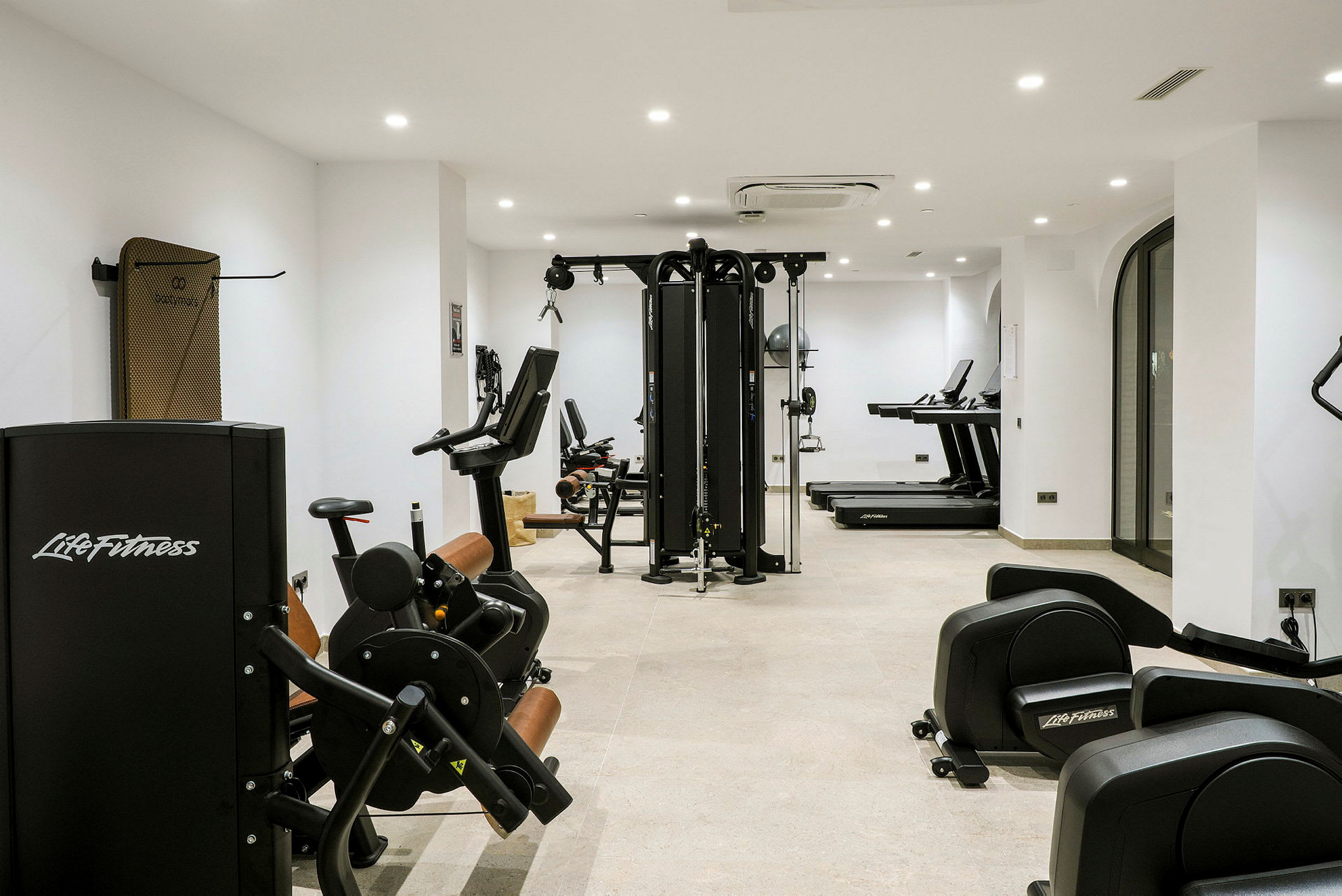 Ett gym med träningsmaskiner och löpband placerade i ett ljust rum. (AI-genererad text)