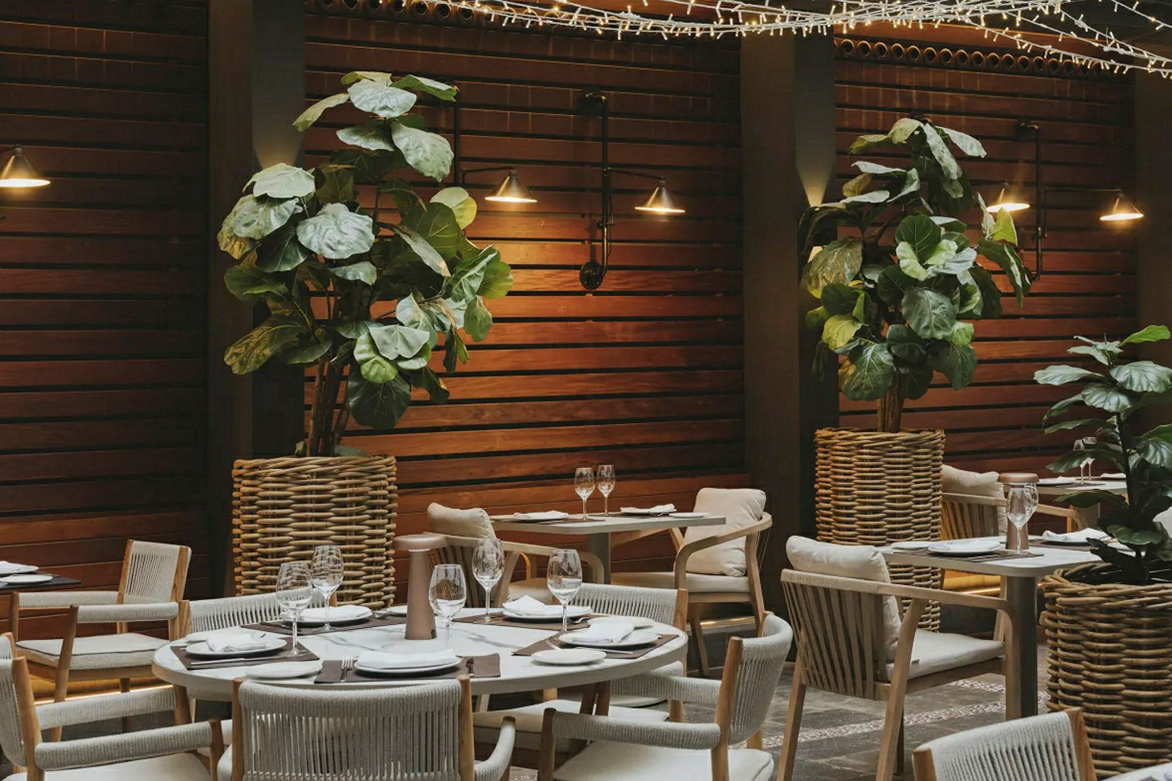 En upplyst restaurang med träpanel, växtdekorationer och dukade bord. (AI-genererad text)