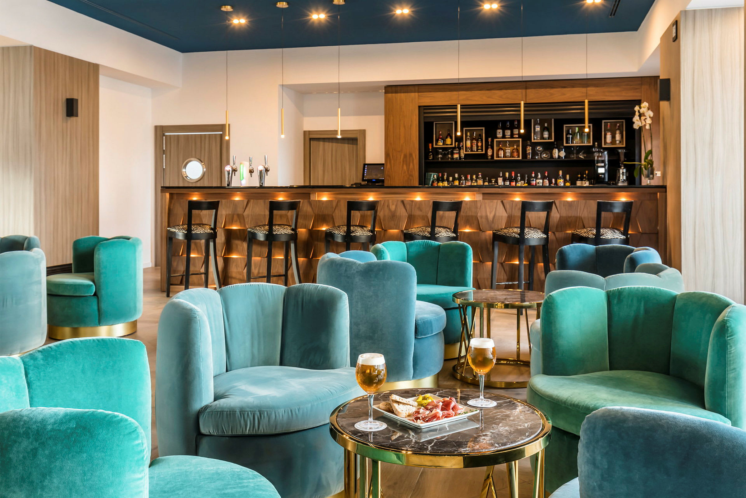 En modern bar med gröna stolar och ett dekorativt upplyst träbart i bakgrunden. (AI-genererad text)