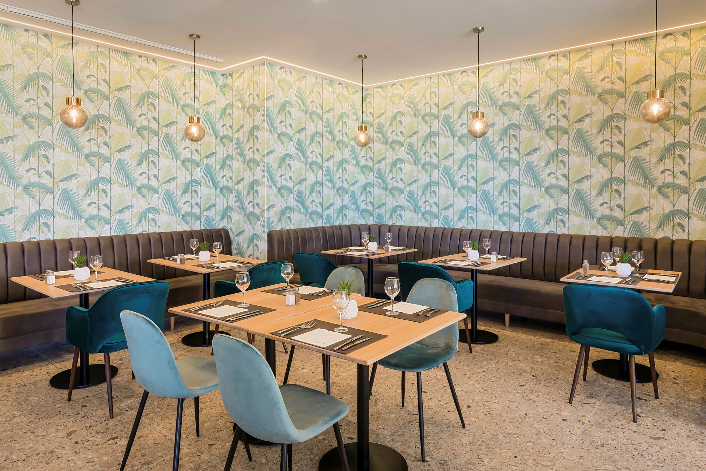 Inredningen i en restaurang med gröna väggar och ett mönster av blad samt träbord omgivna av stoppade stolar. (AI-genererad text)