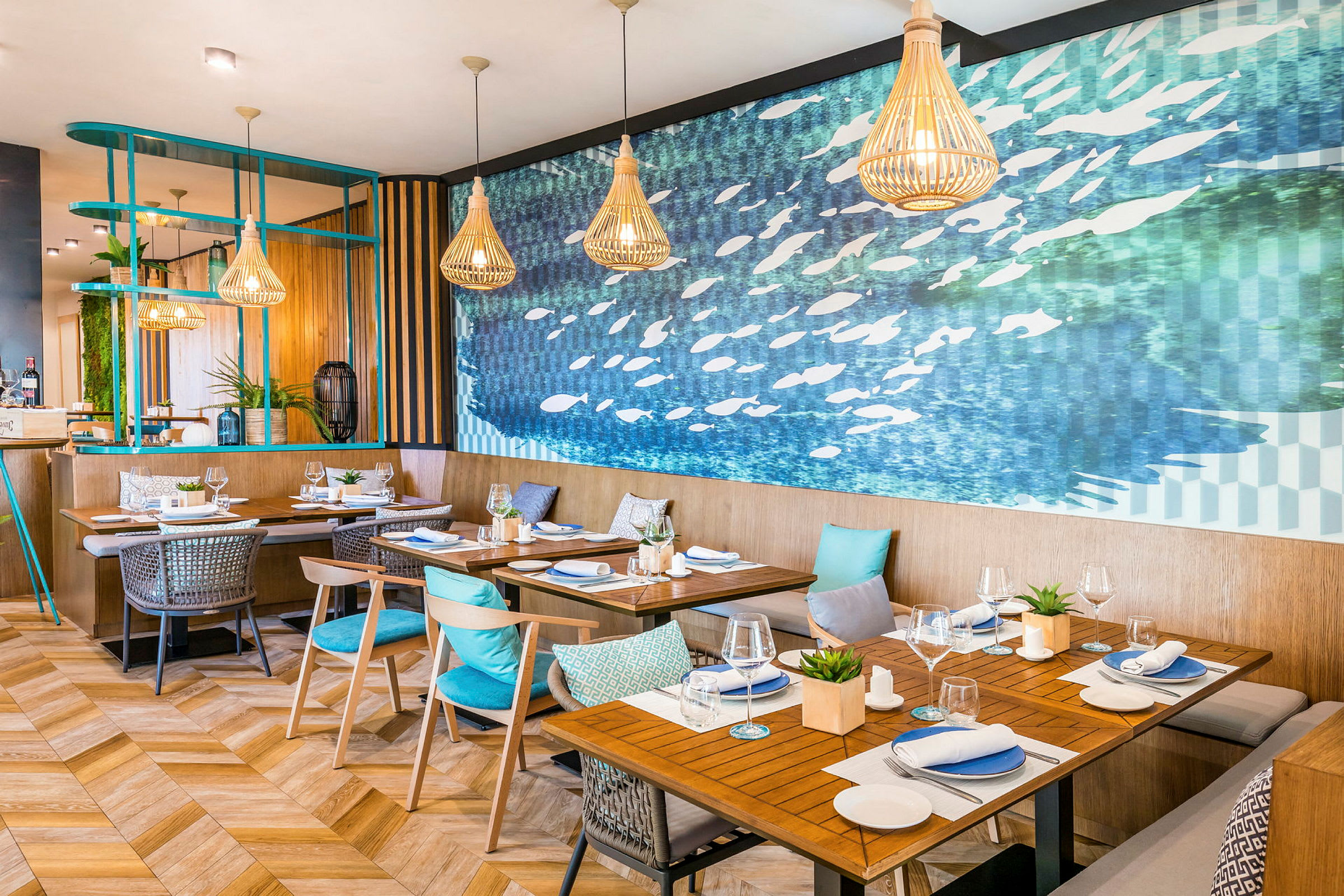 Interiör av en modern restaurang med träbord, stolar och blå kuddar samt en blå abstrakt väggmålning. (AI-genererad text)