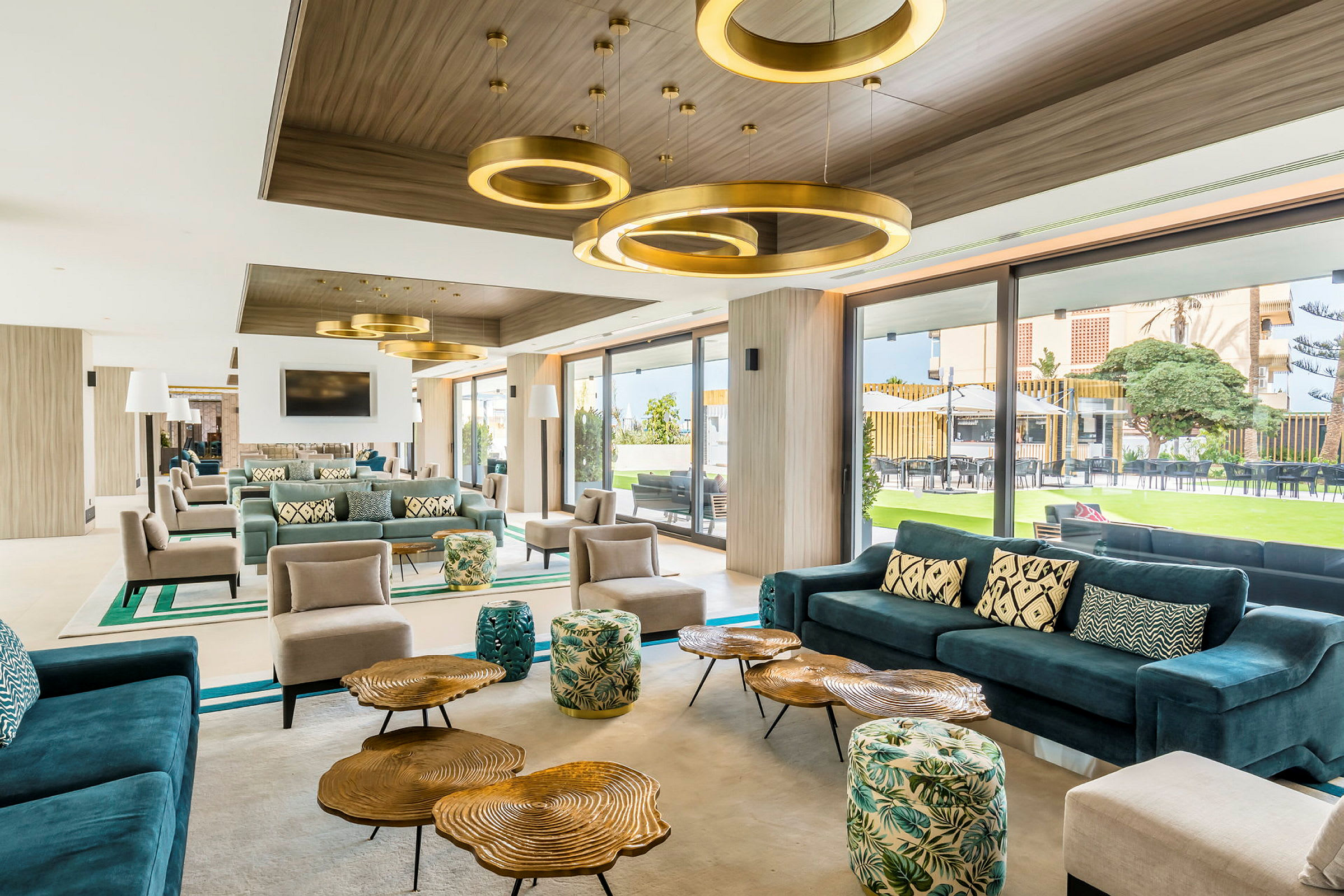 Modernt och stilfullt inredd lounge med färgglada möbler och stora fönster som vetter mot en trädgård. (AI-genererad text)