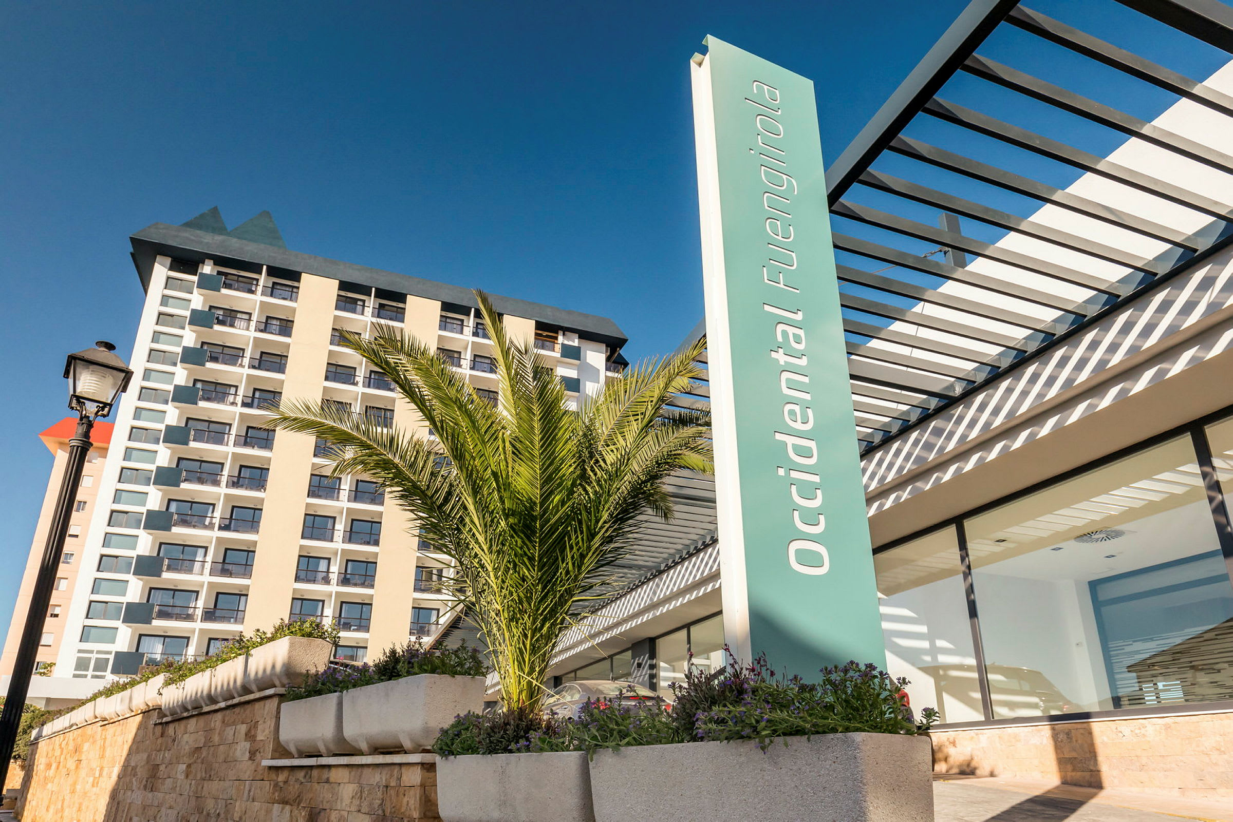 Bild av hotellbyggnad med modern arkitektur, med skylten "Occidental Fuengirola" samt palmer i förgrunden. (AI-genererad text)