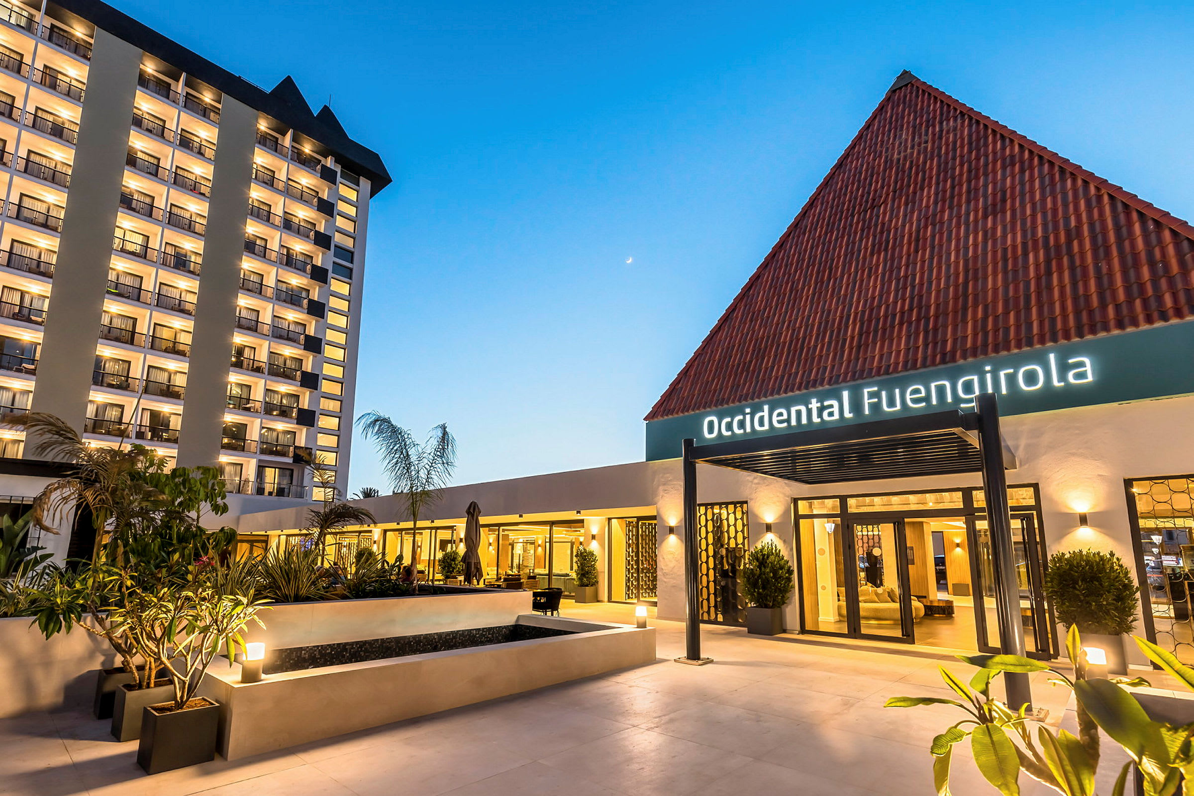 Hotellbyggnad med namnet Occidental Fuengirola, med upplysta fasader och ingången omgiven av växter. (AI-genererad text)