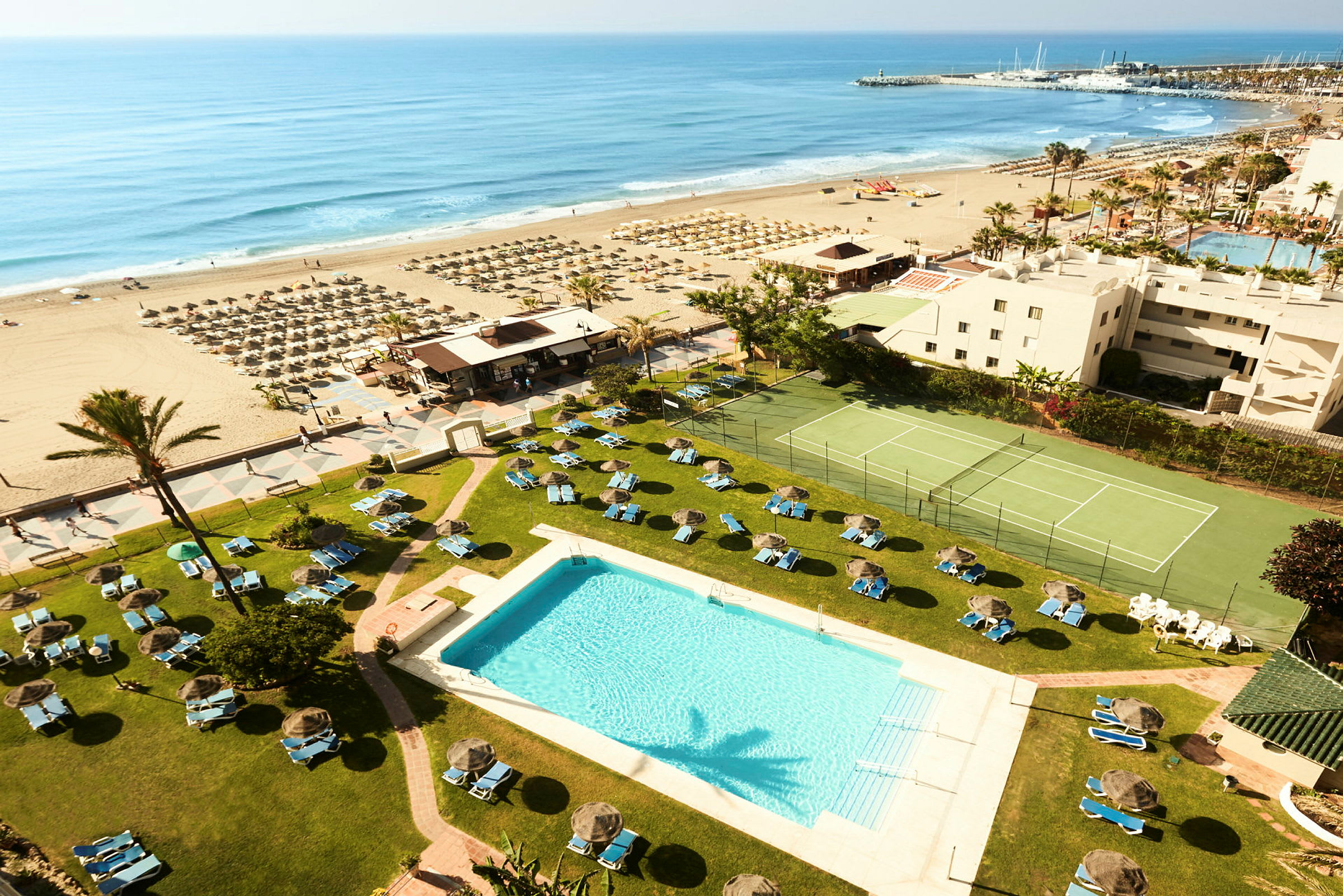 Hotellets poolområde med utsikt över stranden och havet. (AI-genererad text)