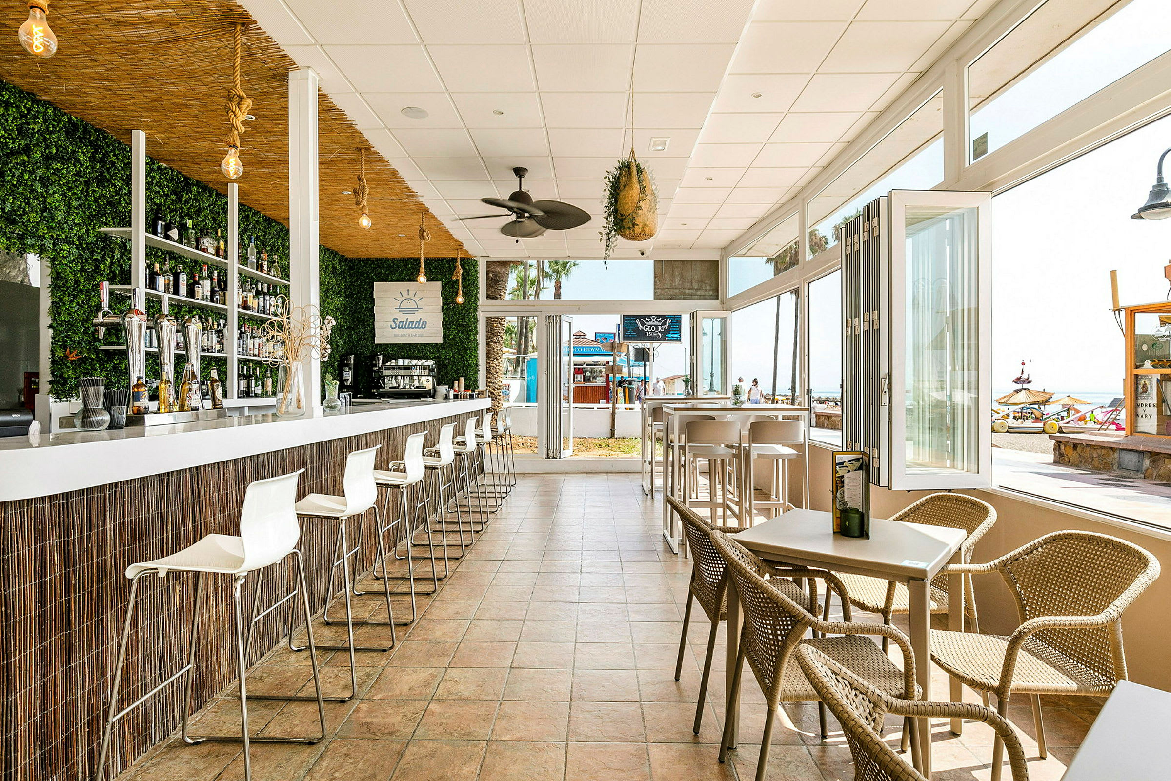 Utsikt över en modern bar med stålrörsstolar och en vägg med grönska. (AI-genererad text)