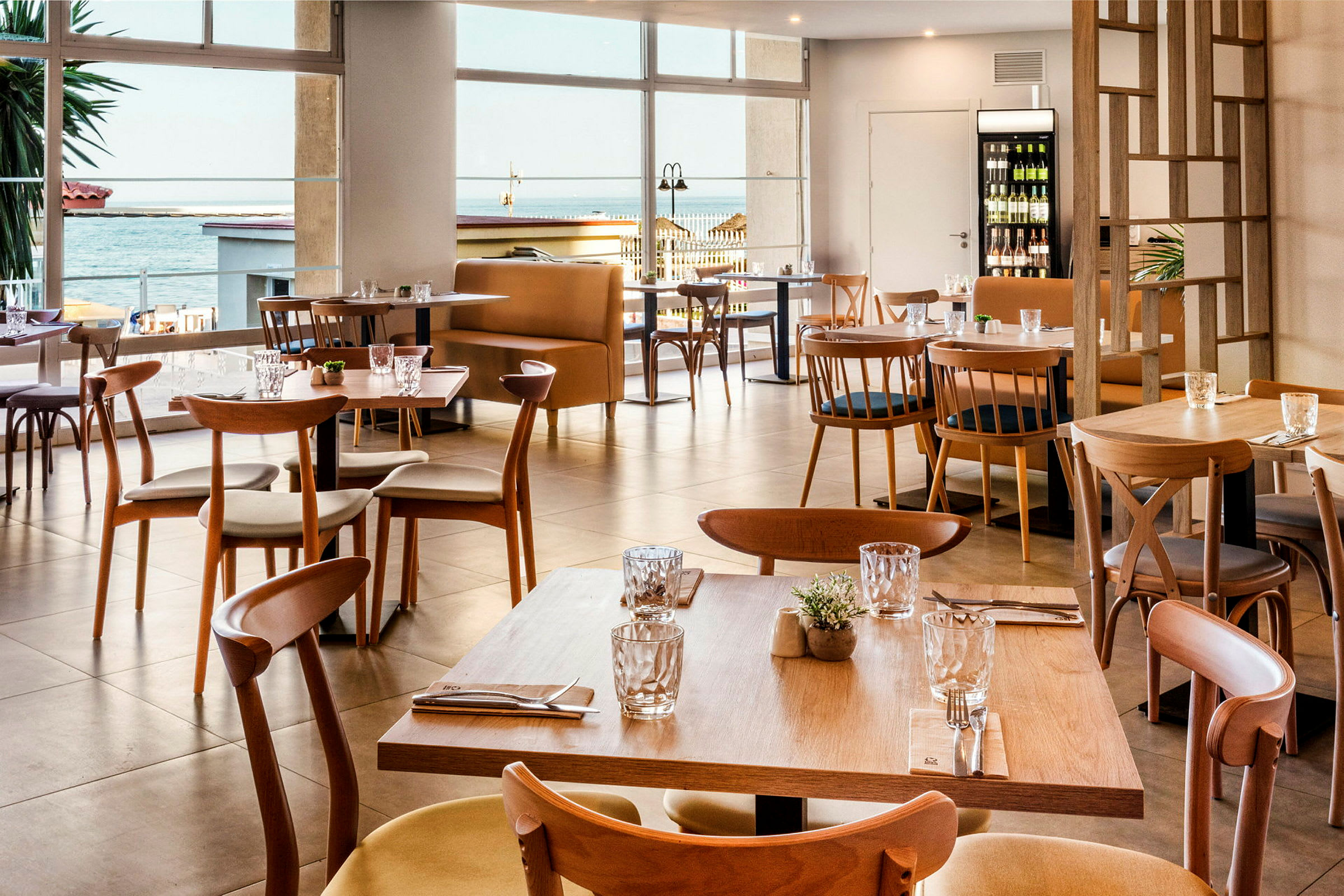Moderna bord och stolar i trä i en restaurang med sjöutsikt. (AI-genererad text)