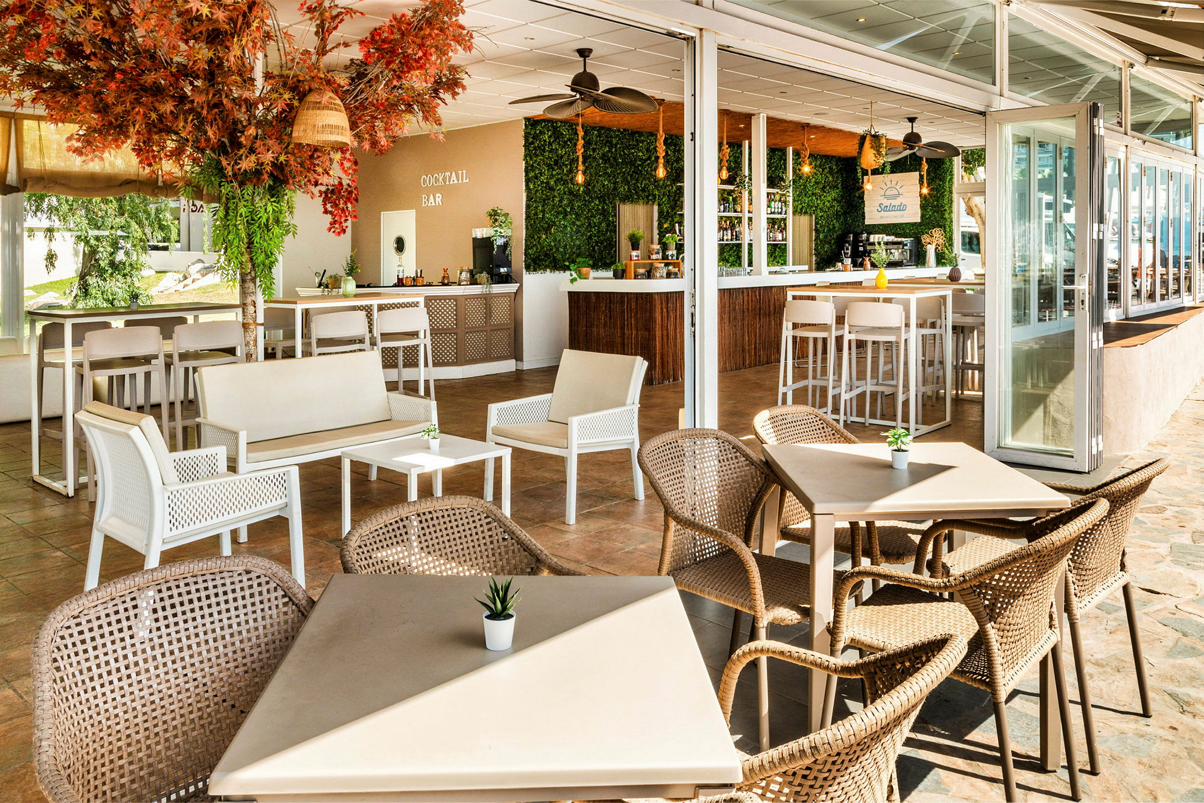 En öppen loungedel med bord och stolar nära en cocktailbar. (AI-genererad text)