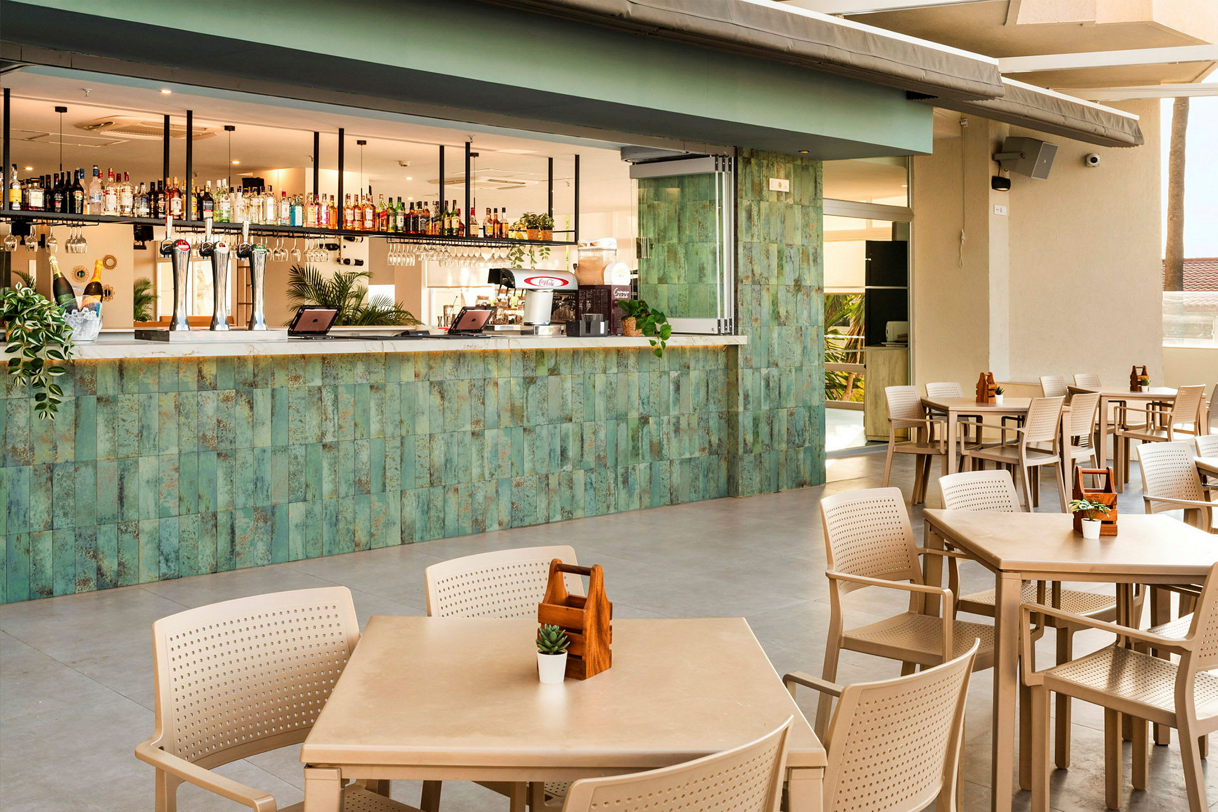 En bar med grön kakel på framsidan och bord och stolar för sittplatser framför. (AI-genererad text)
