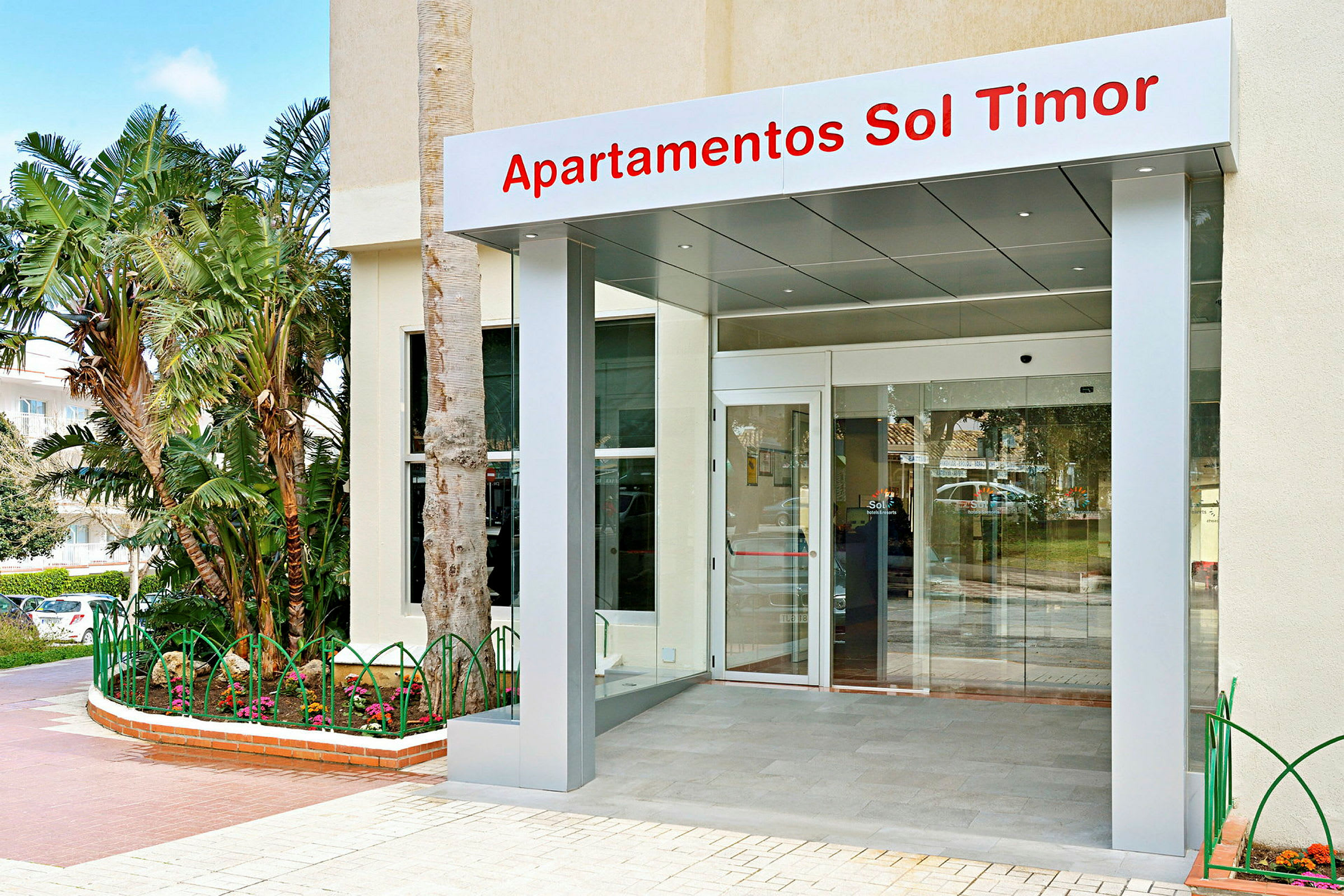 Entrén till Sol Timor Apartments med glasdörr och skylt. (AI-genererad text)