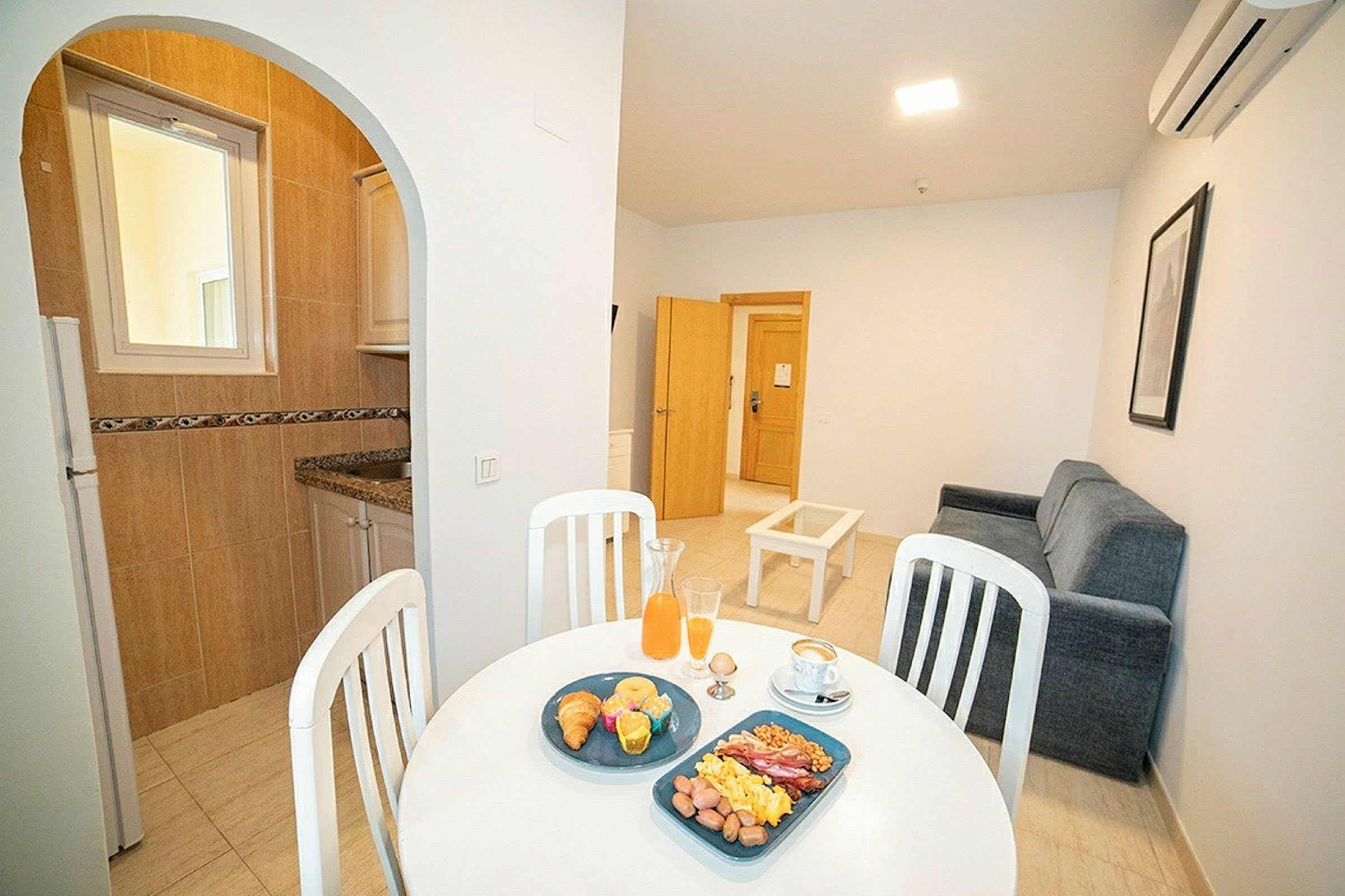 Bild av en lägenhet med köksdel och vardagsrum, samt ett dukat bord med frukost. (AI-genererad text)
