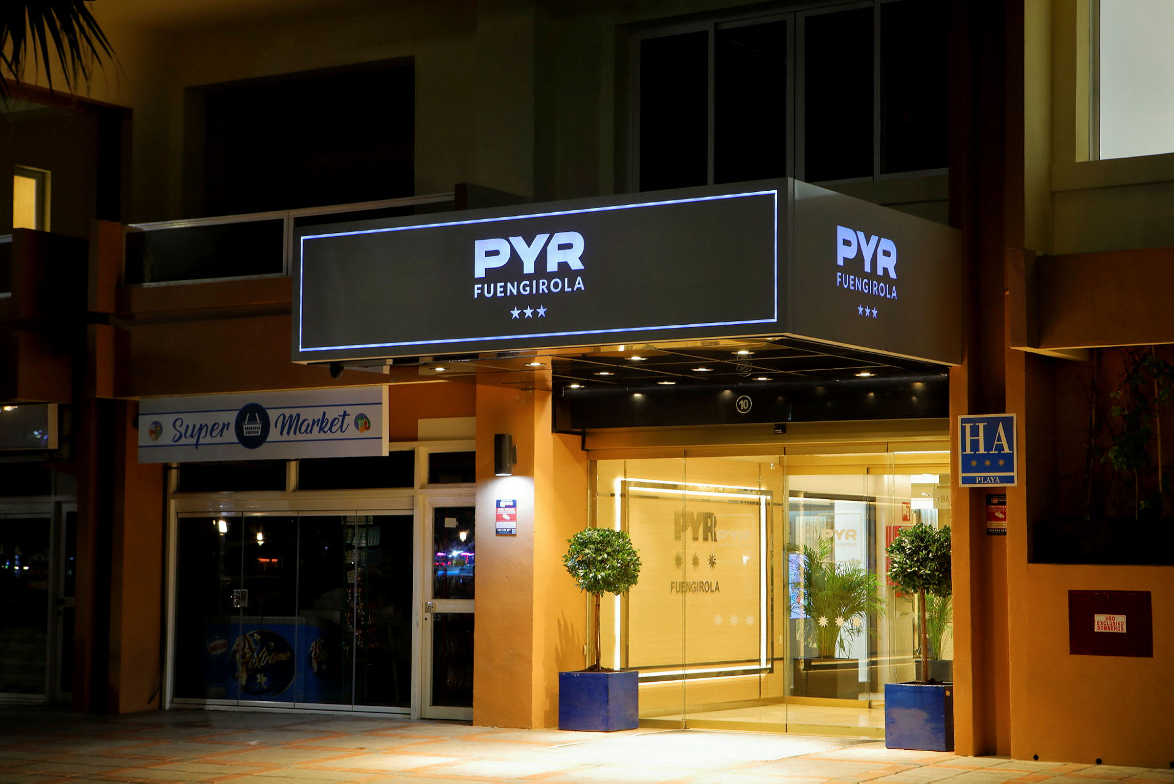Hotellentrén till PYR Fuengirola med belysning och skyltar. (AI-genererad text)