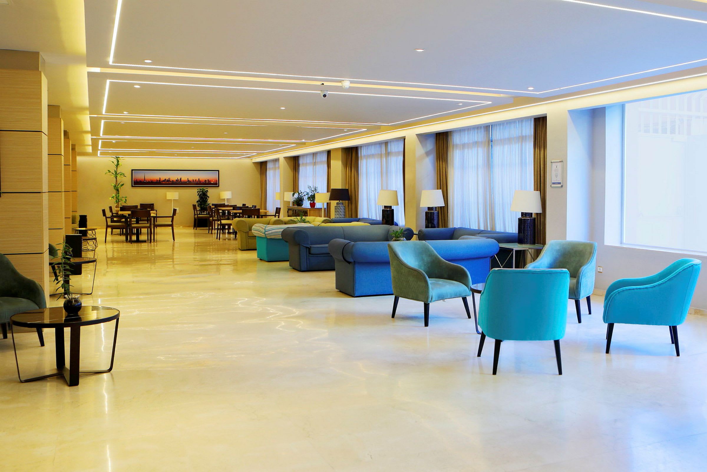 En rymlig hotellobby med olika sittplatser och bord, dekorerad med lampor och växter. (AI-genererad text)