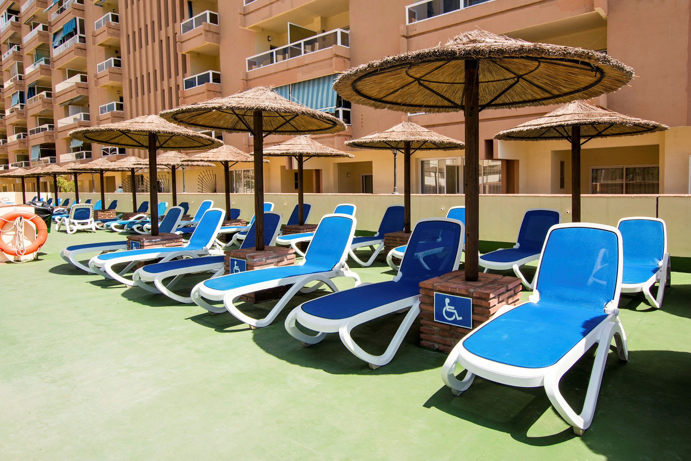 Solstolar med parasoll vid en hotellterrass. (AI-genererad text)