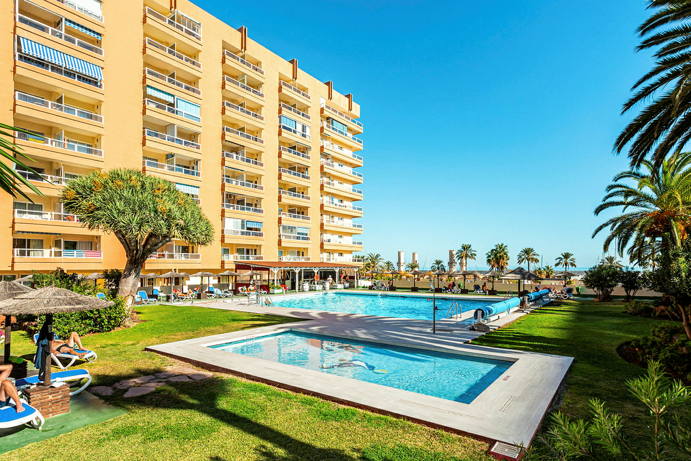Hotellbyggnad med pool och trädgård. (AI-genererad text)