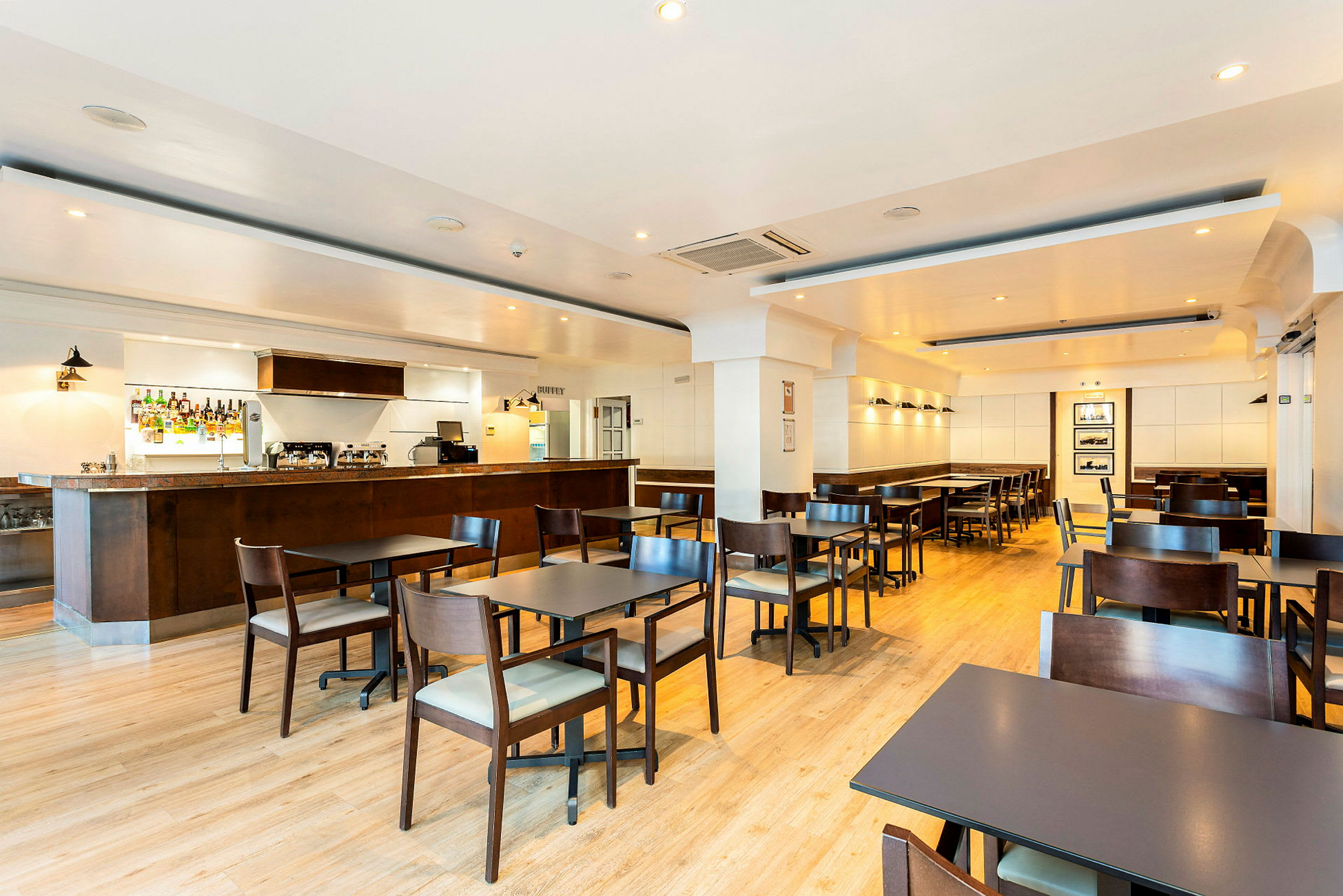 Ett hotellrestaurangområde med bord och stolar samt en bardisk. (AI-genererad text)