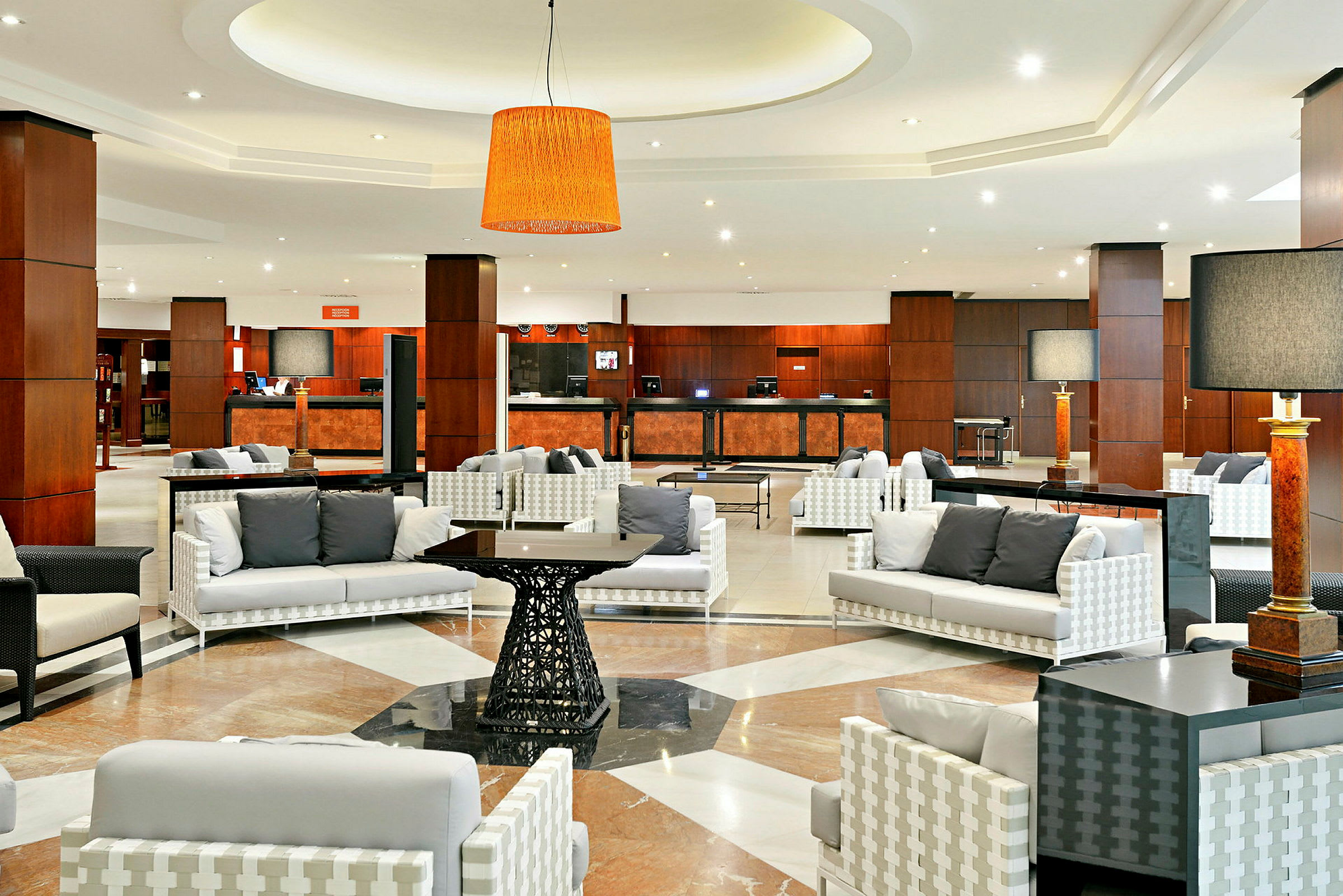 Ett modernt hotellobbyområde med sittgrupper och reception i bakgrunden. (AI-genererad text)
