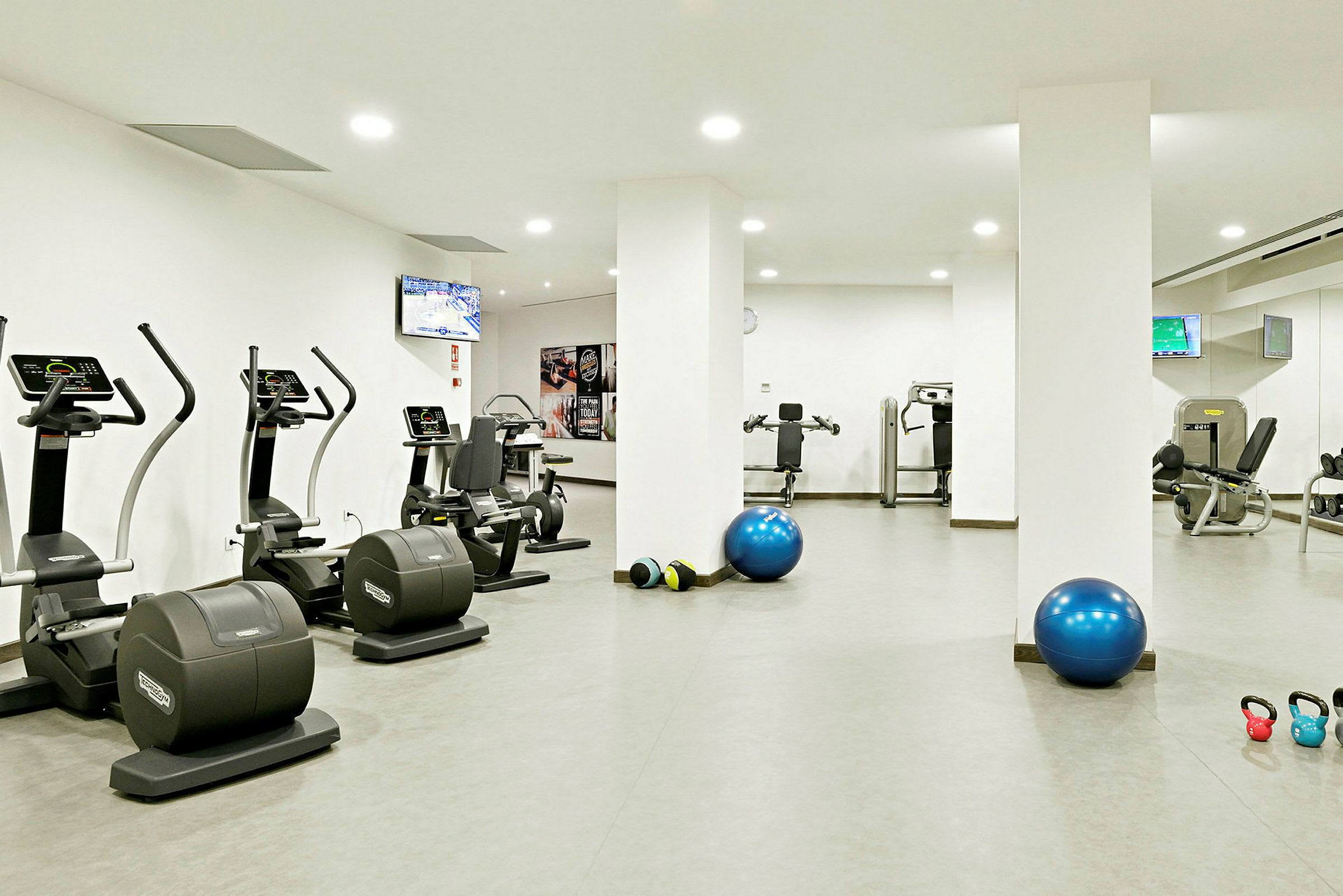 Ett gym med träningsmaskiner, träningsbollar och kettlebells. (AI-genererad text)