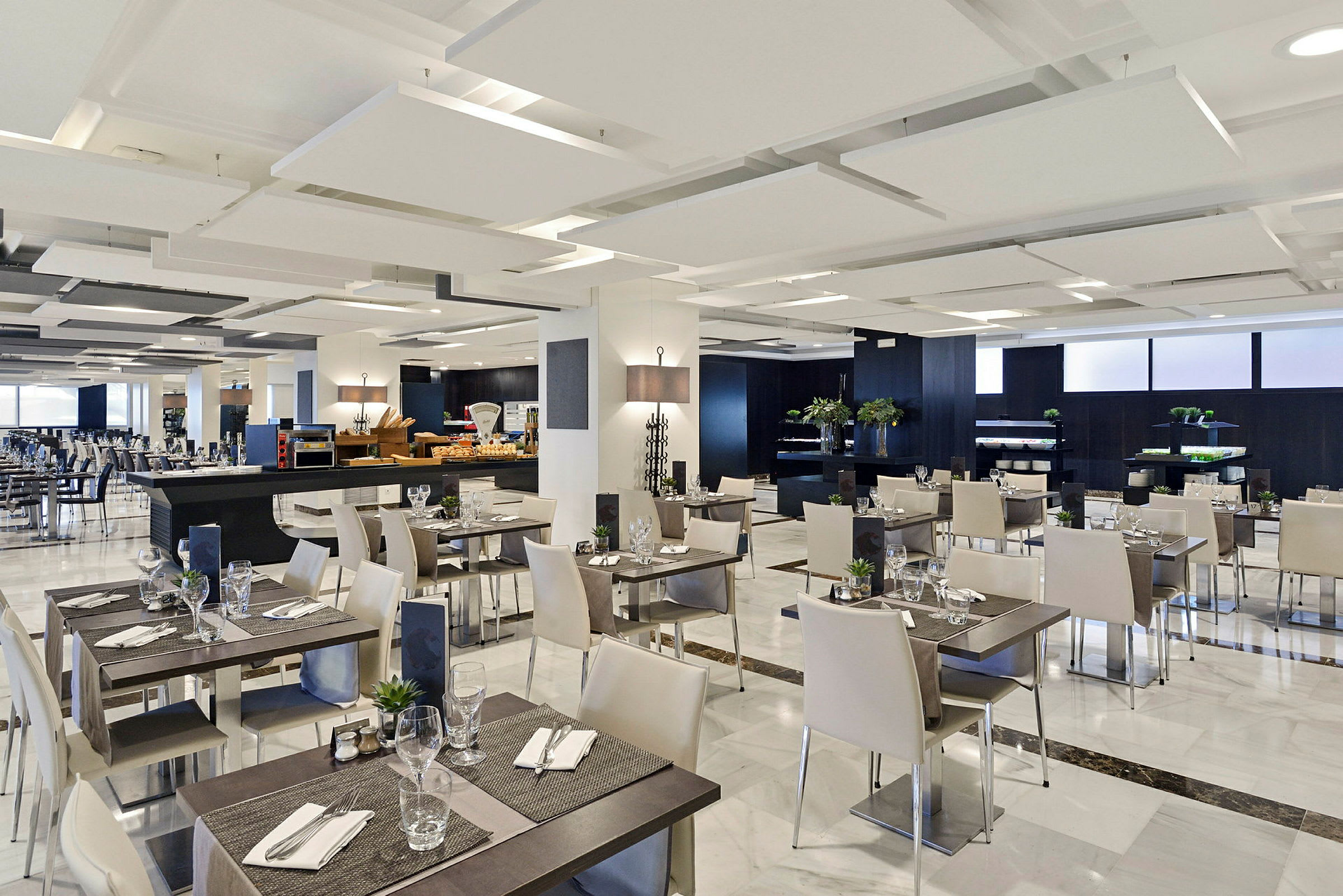 En modern restaurang med vit inredning och dukade bord. (AI-genererad text)