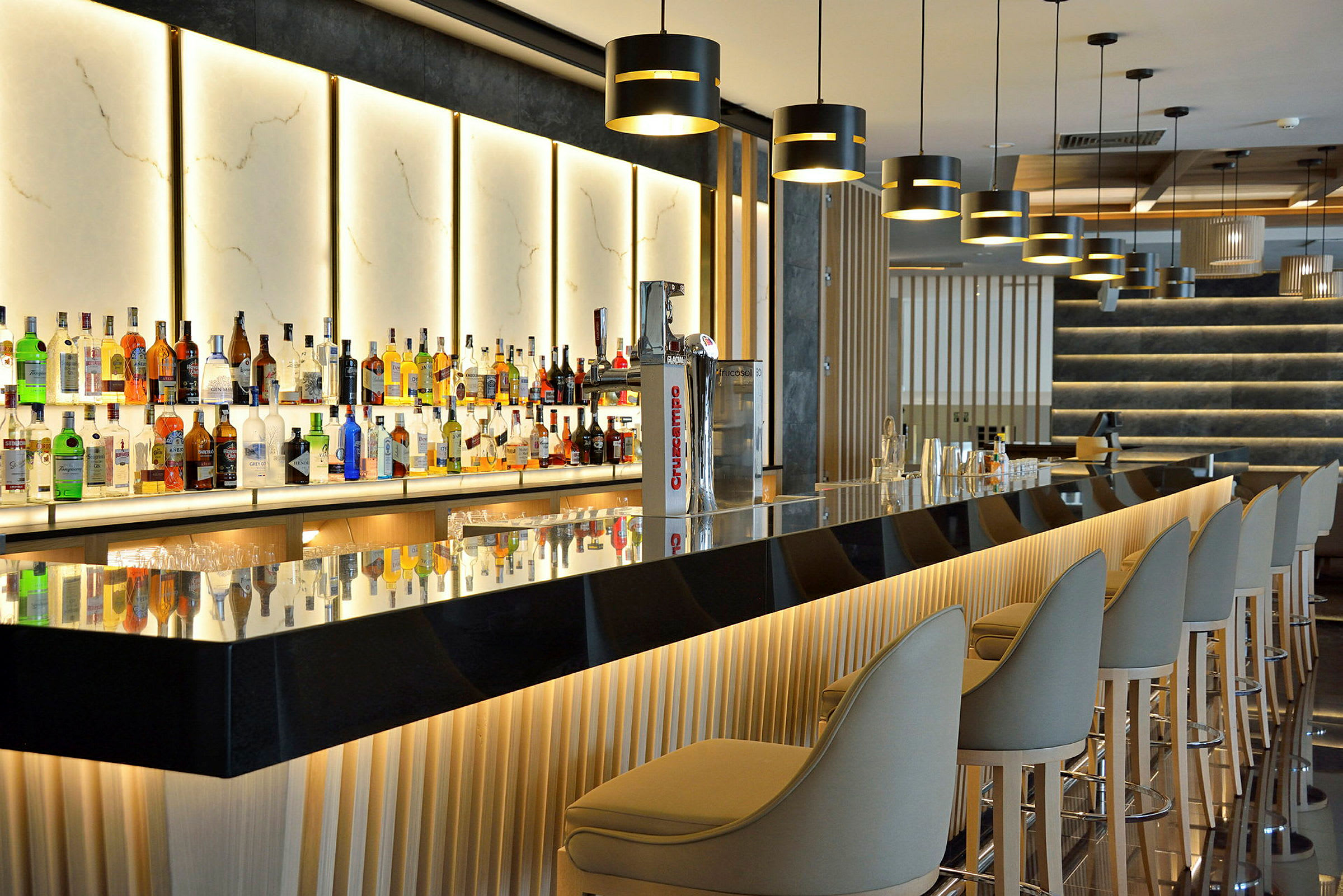 En modern bar med upplysta flaskhyllor och eleganta sittplatser. (AI-genererad text)