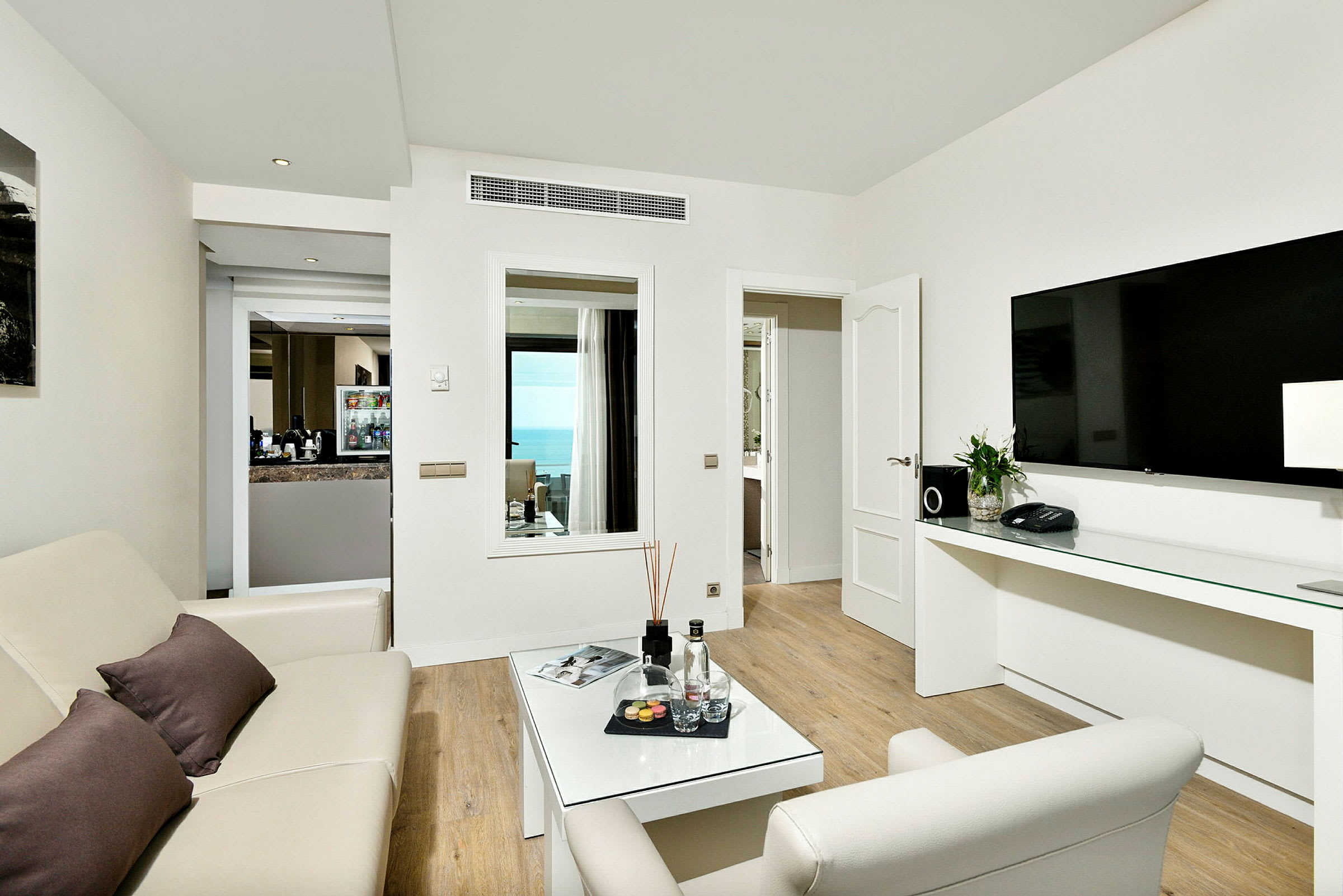 Ett hotellrum med vardagsrum, soffa, soffbord, stor TV och fin havsutsikt. (AI-genererad text)
