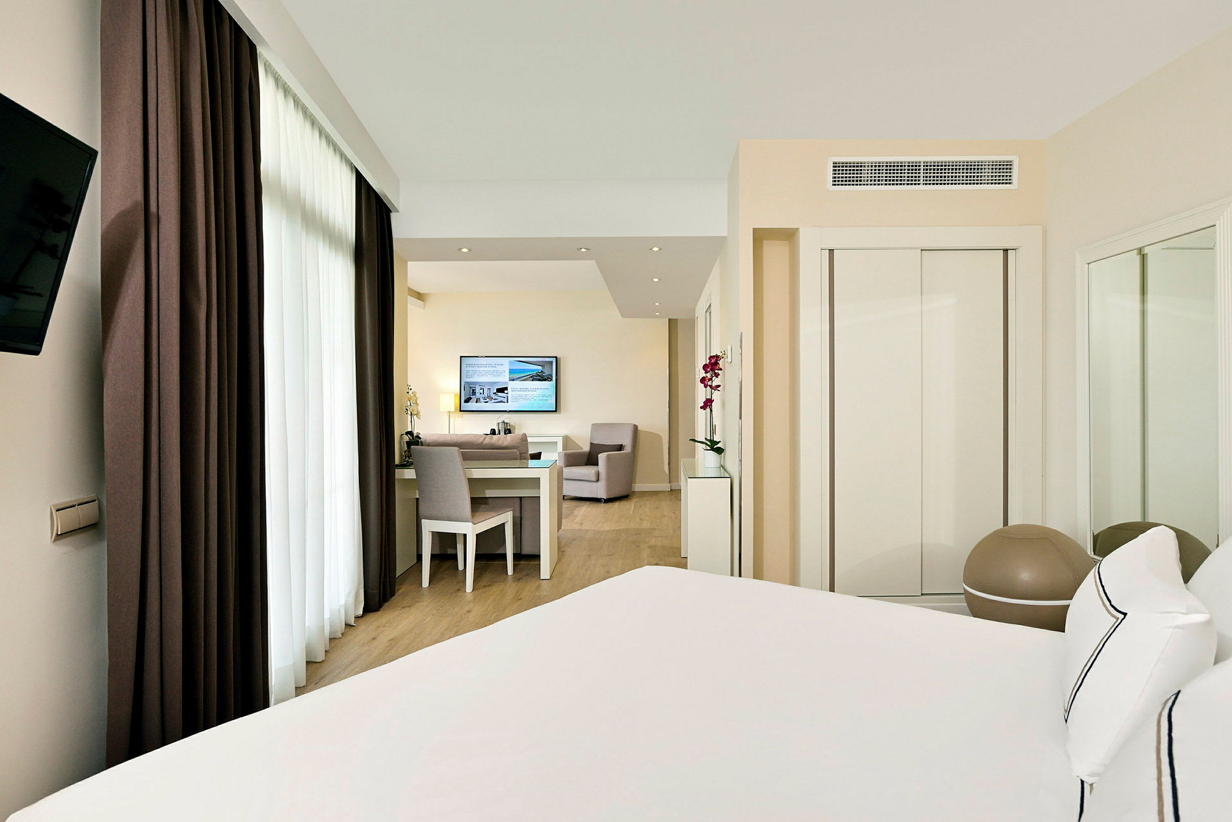 Inblick i ett hotellrum nära sängen, med ett skrivbord och sittgrupp i bakgrunden. (AI-genererad text)