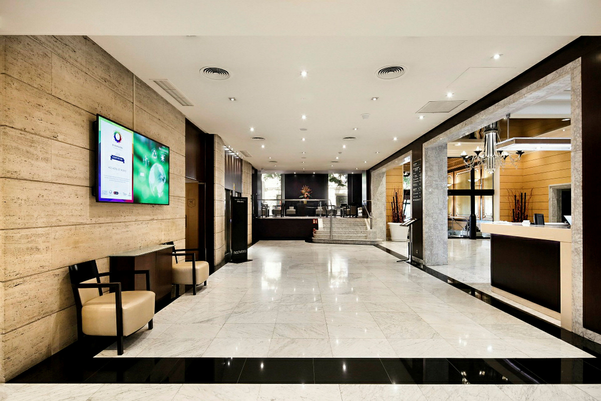 En bild av ett hotellobbyområde med marmorgolv, en reception och sittplatser på sidorna. (AI-genererad text)