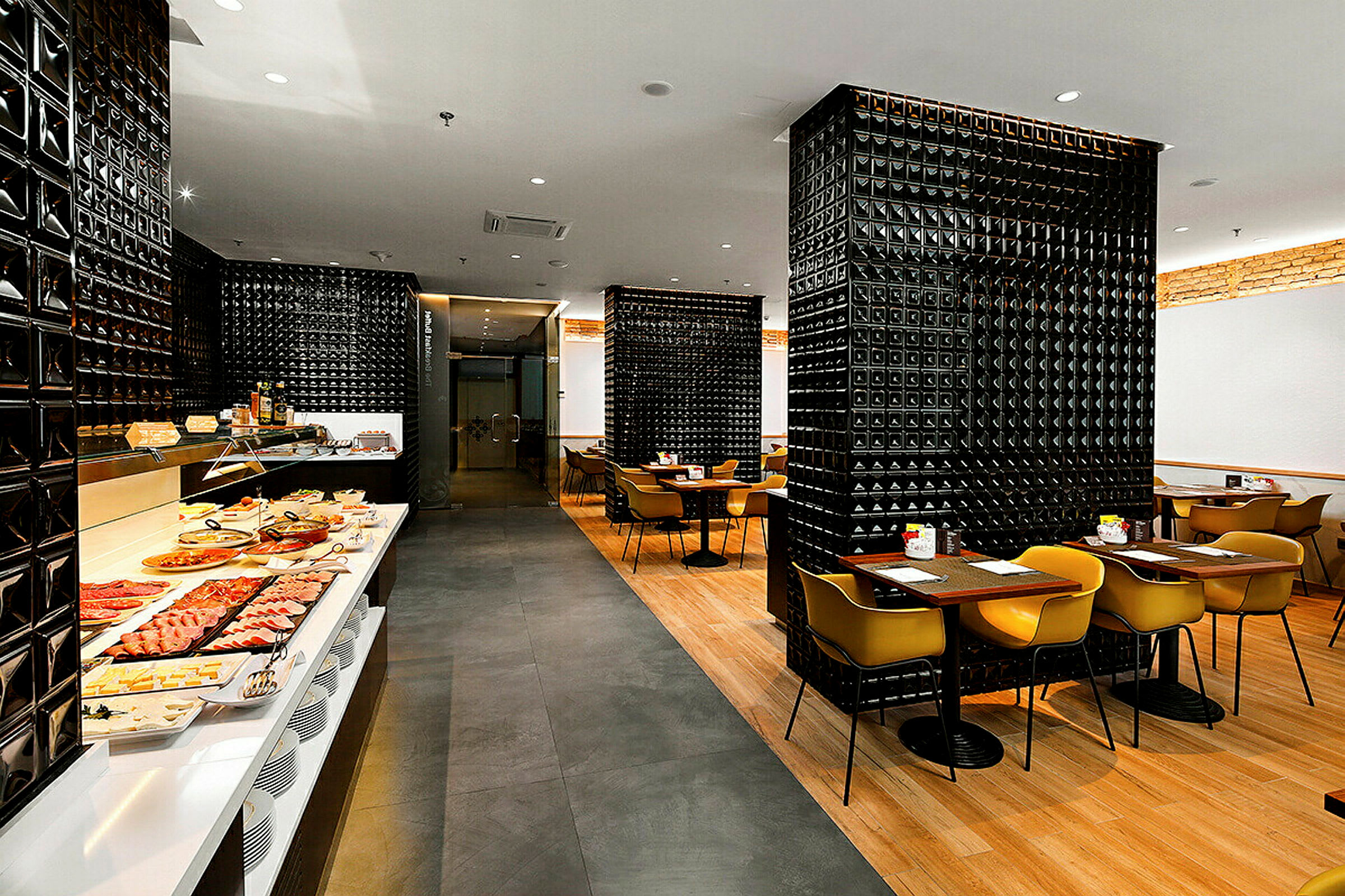 Restaurang med svartmönstrade väggar, en frukostbuffé och matplatser med moderna möbler. (AI-genererad text)