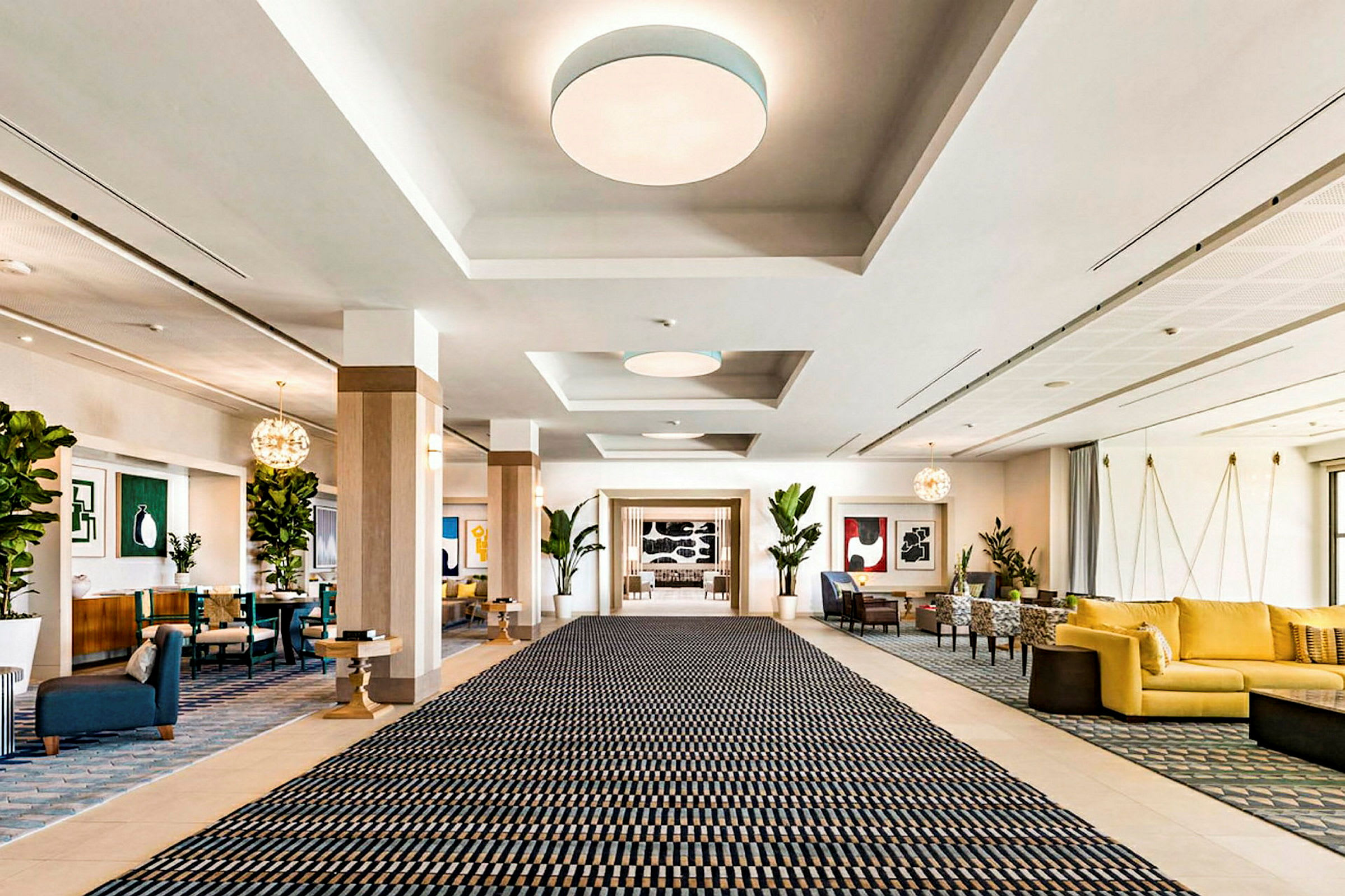 En rymlig hotellobby med en stor matta, sittgrupper och dekorationer. (AI-genererad text)