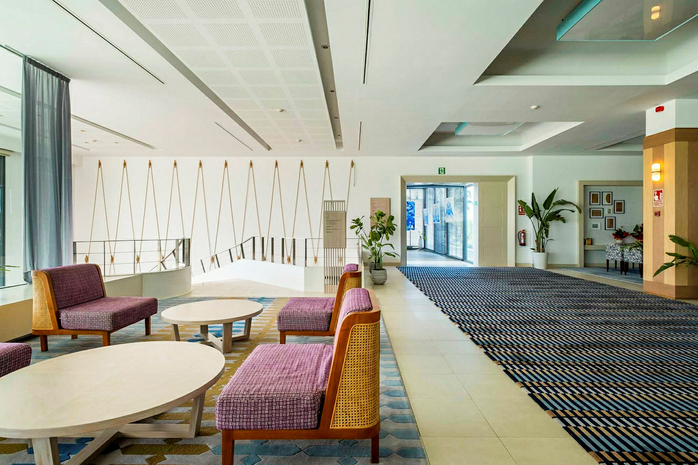 Ett modernt hotellobbymiljö med sittmöbler, väggdekorationer och växtarrangemang. (AI-genererad text)