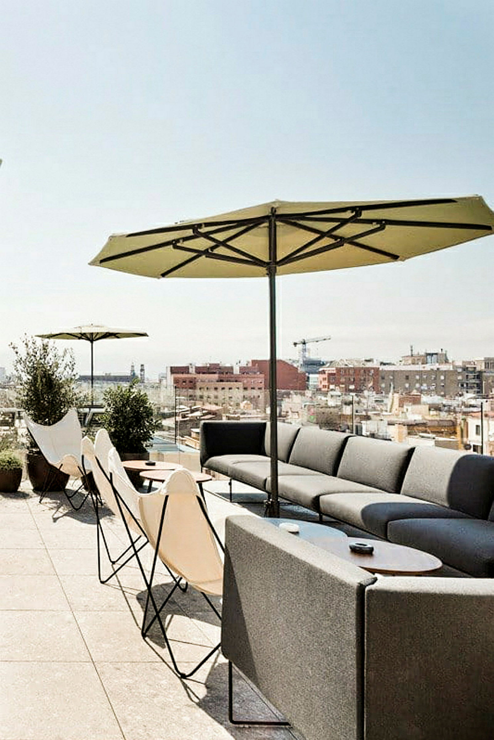 Bild av en terrass med sittmöbler, parasoller och utsikt över stadens hustak. (AI-genererad text)