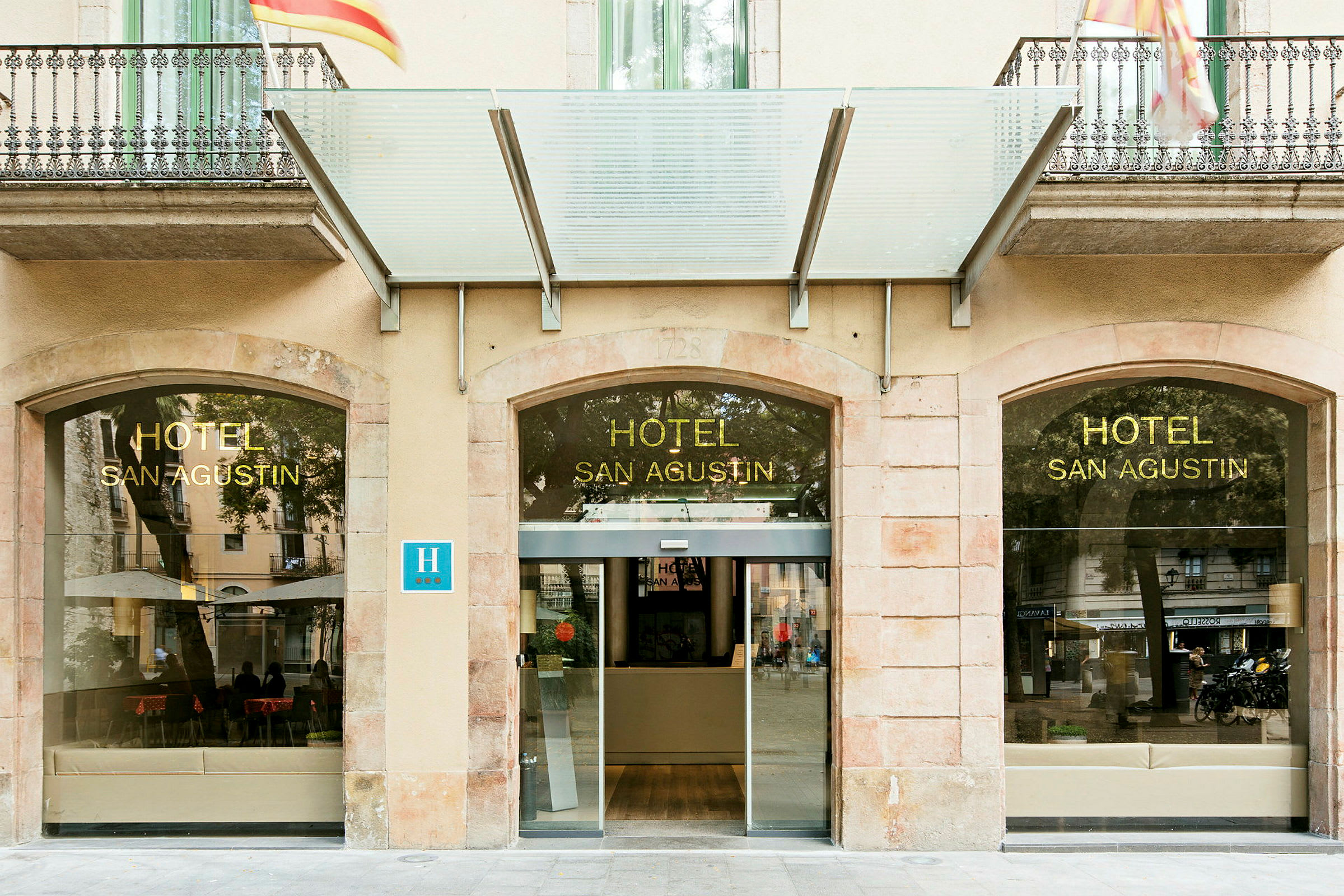 Hotellentré med glasfasad och skylt med texten 'HOTEL SAN AGUSTIN'. (AI-genererad text)