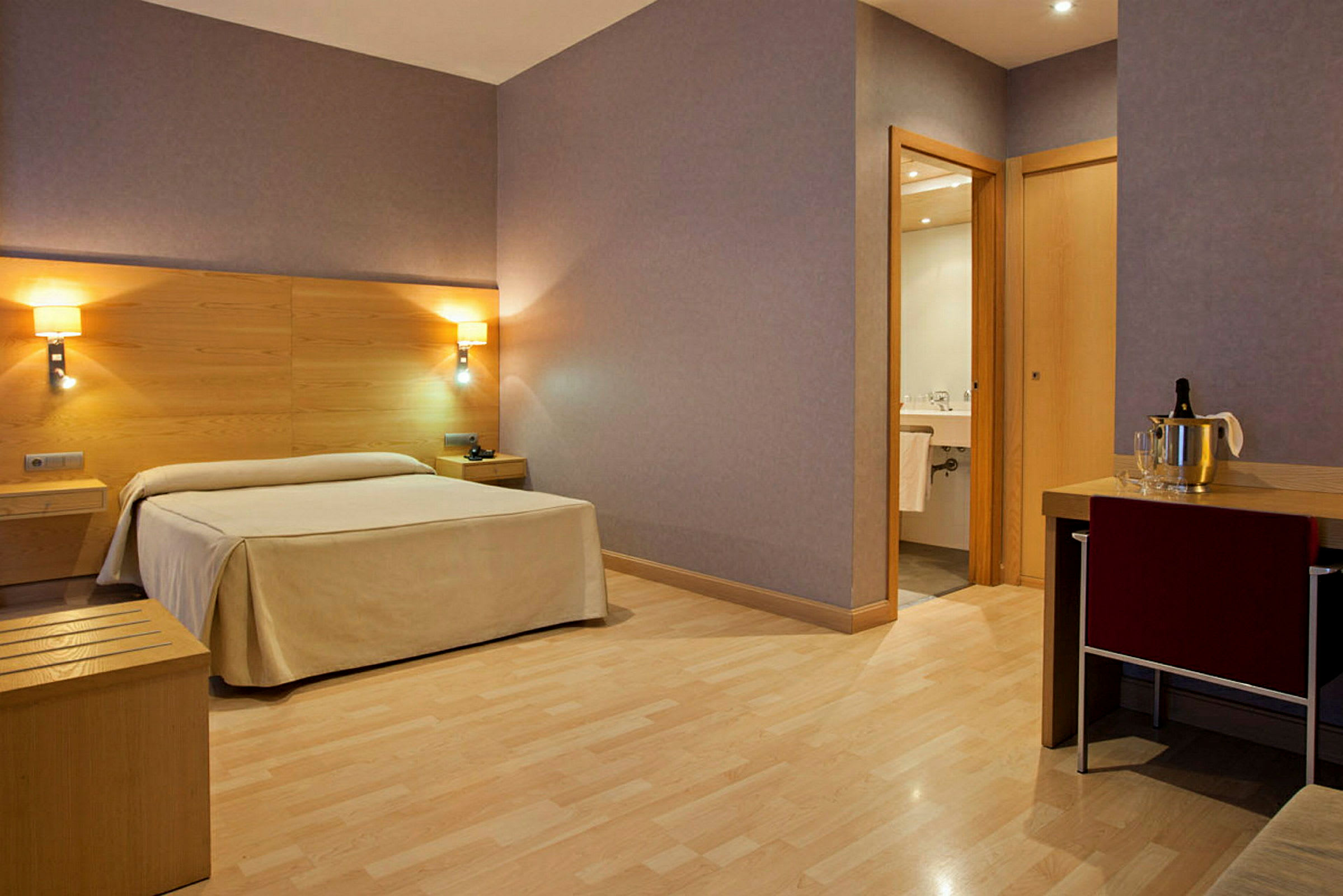 Hotellrum med en säng, nattduksbord, ett skrivbord och ett badrum. (AI-genererad text)