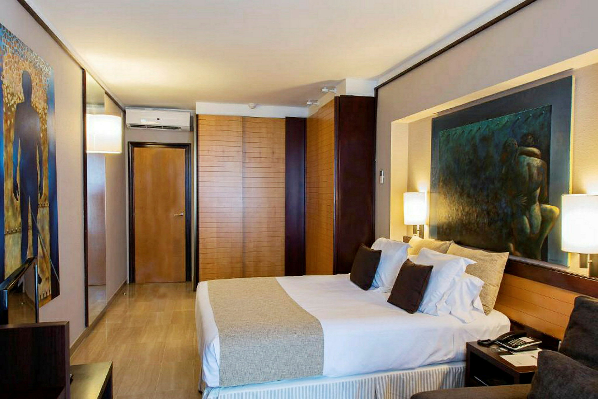 Ett modernt hotellrum med en dubbelsäng, målningar på väggarna och elegant inredning. (AI-genererad text)