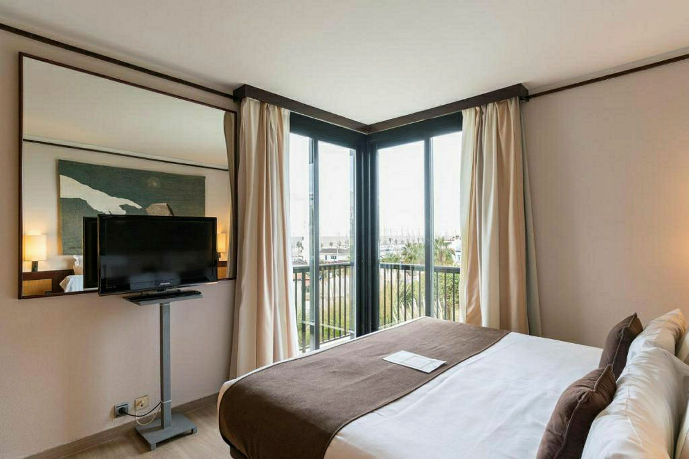 Ett hotellrum med en dubbelsäng, väggmonterad TV och stora fönster med utsikt. (AI-genererad text)