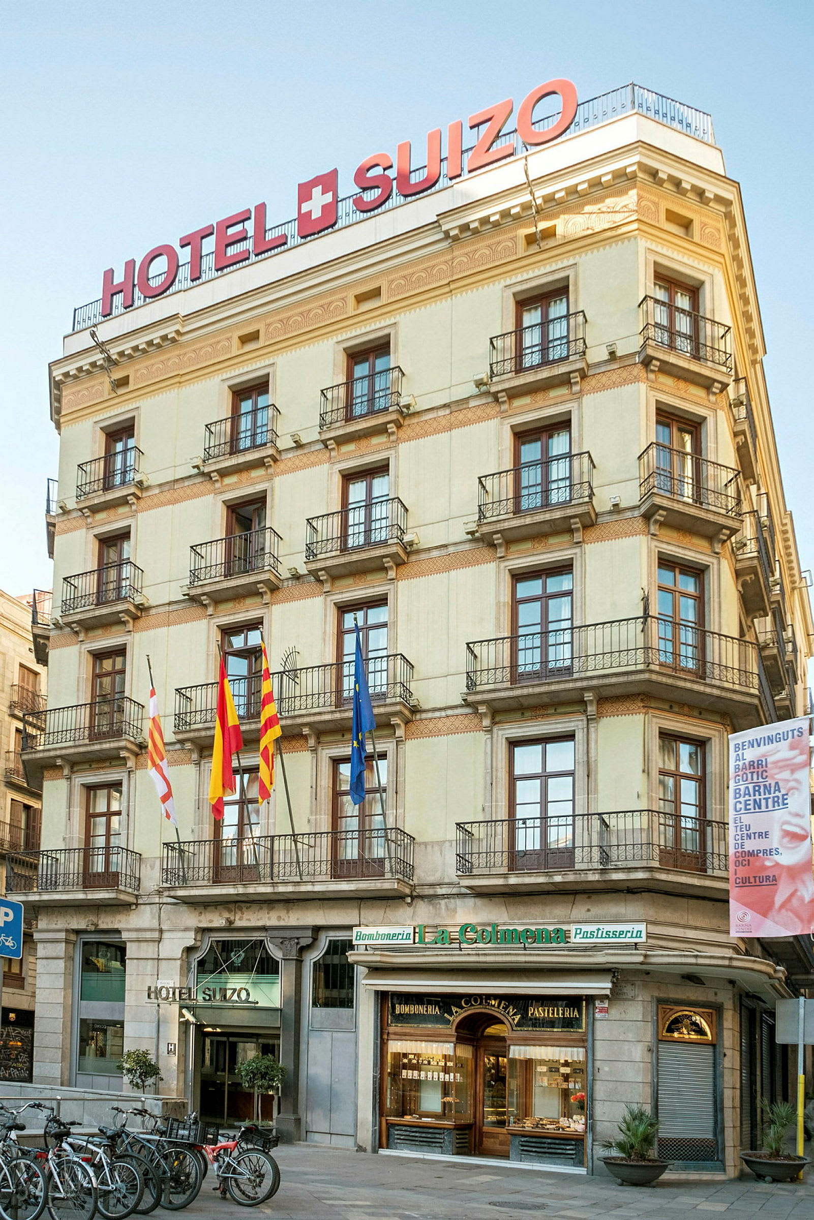 Fasad av hotell Hotel Suizo med skyltar, fönster och balkonger. (AI-genererad text)