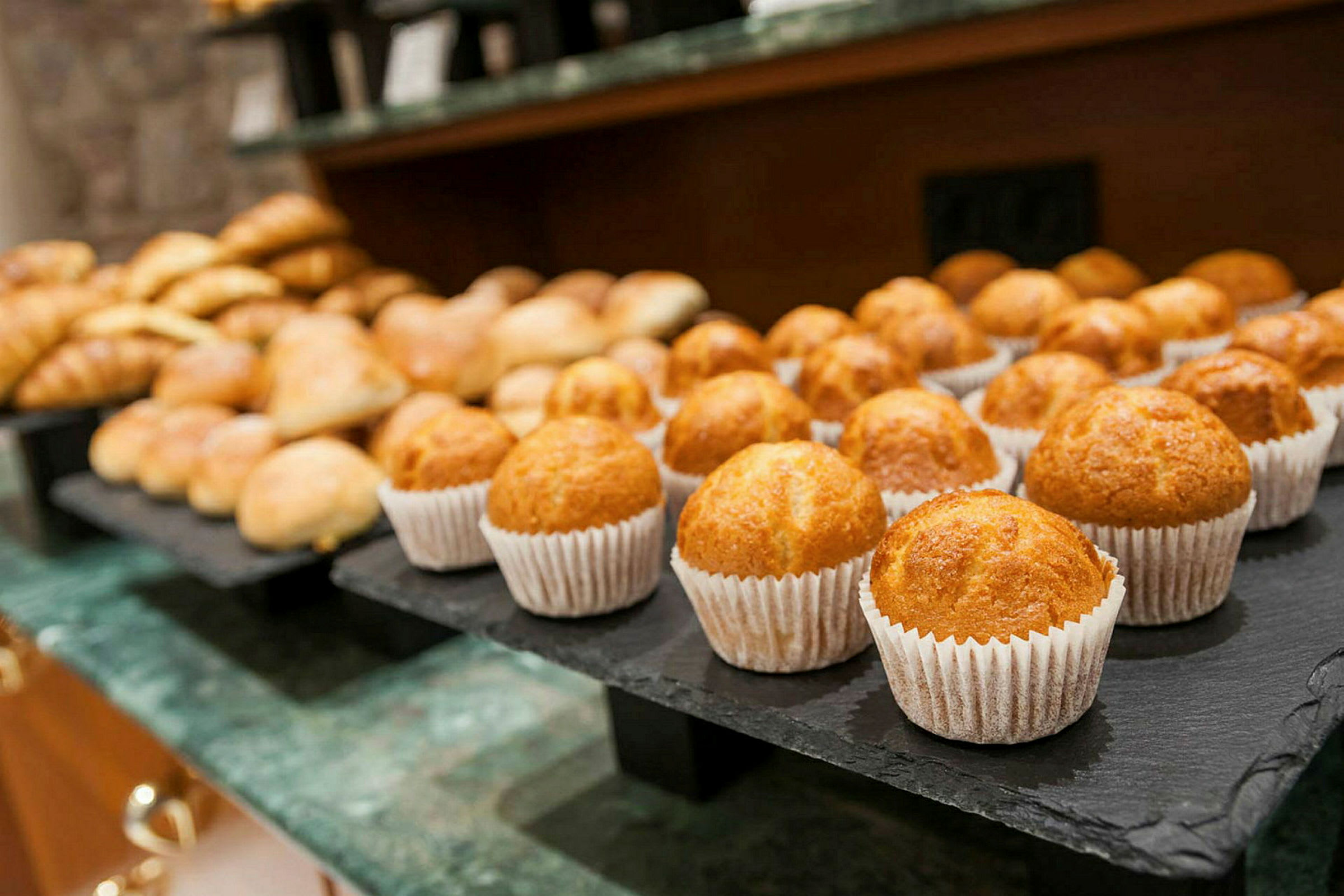 En närbild på ett fat med muffins och andra bakverk på ett bord. (AI-genererad text)
