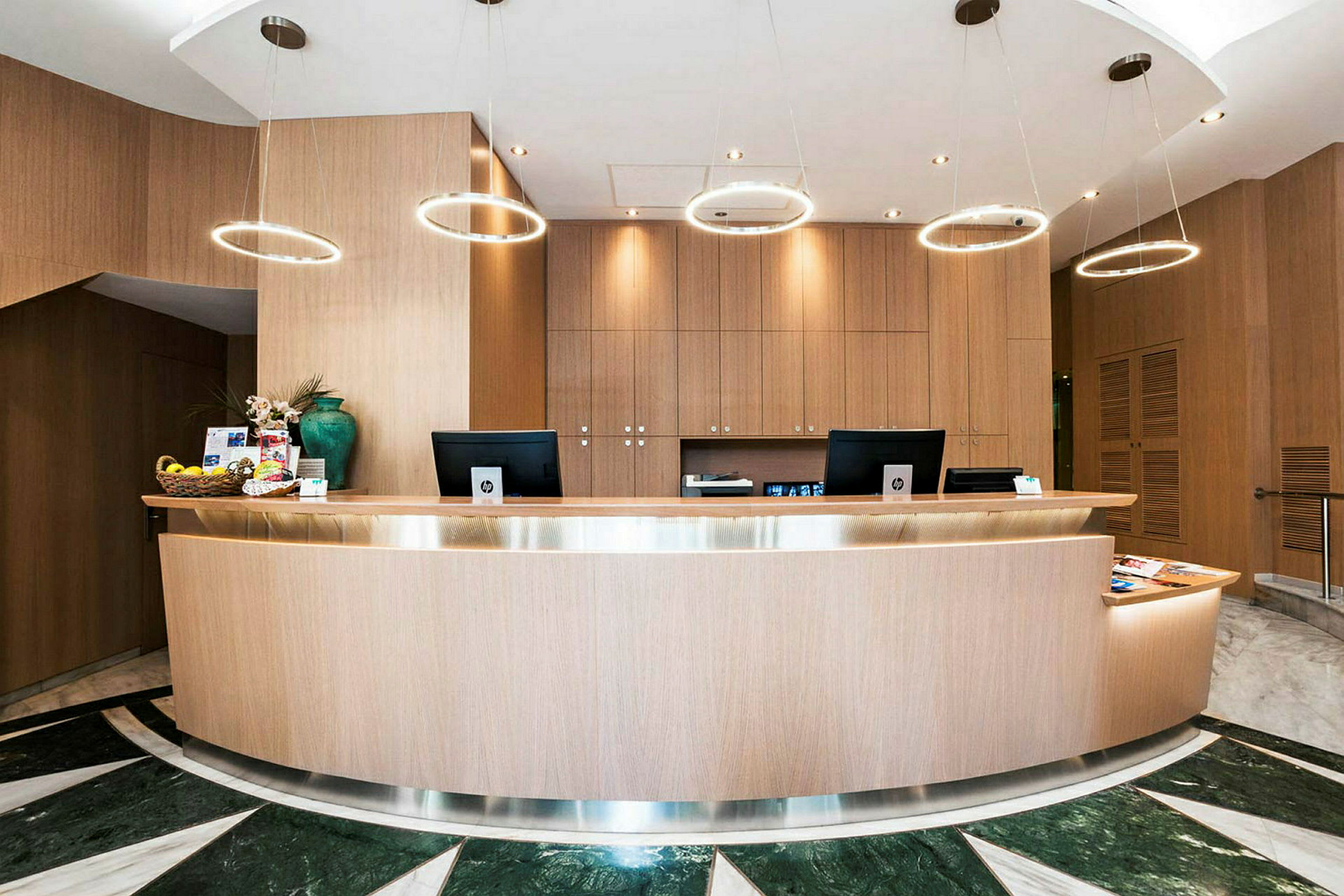 En receptionsdisk i trä med moderna lampor hängandes ovanför och en elegant design. (AI-genererad text)