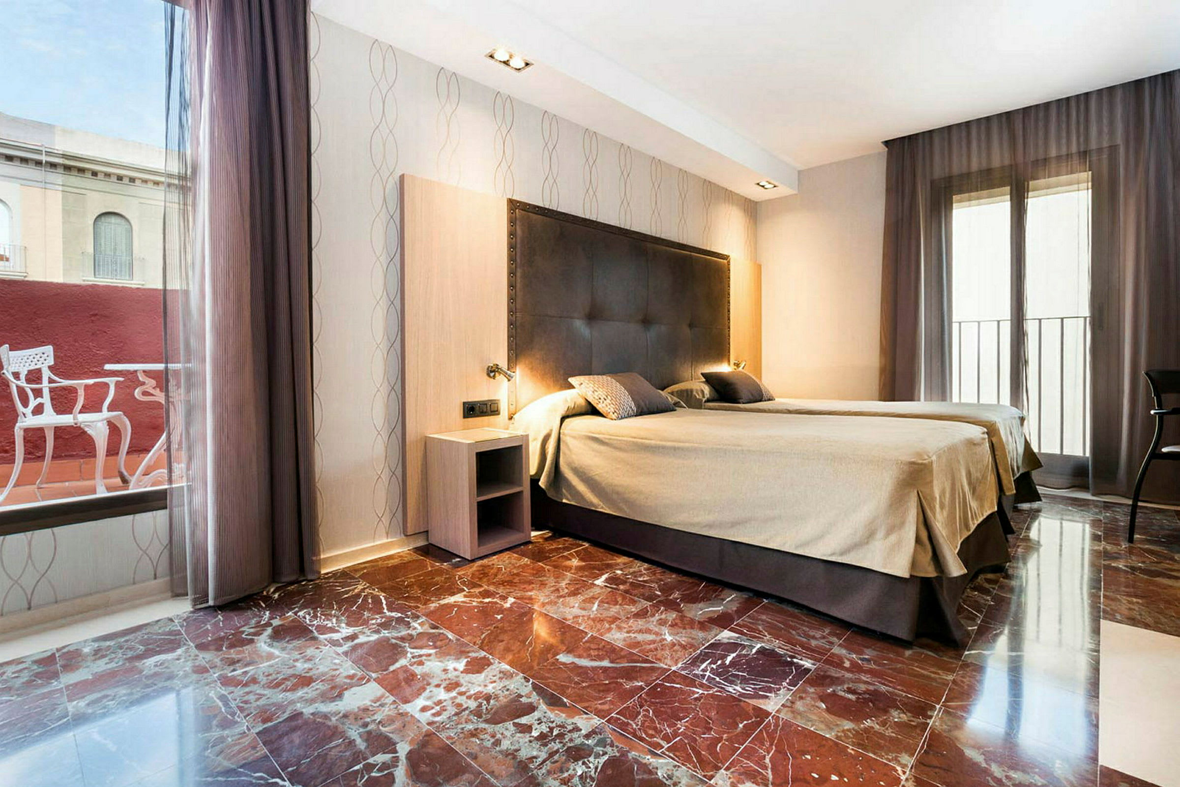 Ett hotellrum med två enkelsängar, marmorgolv och stora fönster med gardiner. (AI-genererad text)