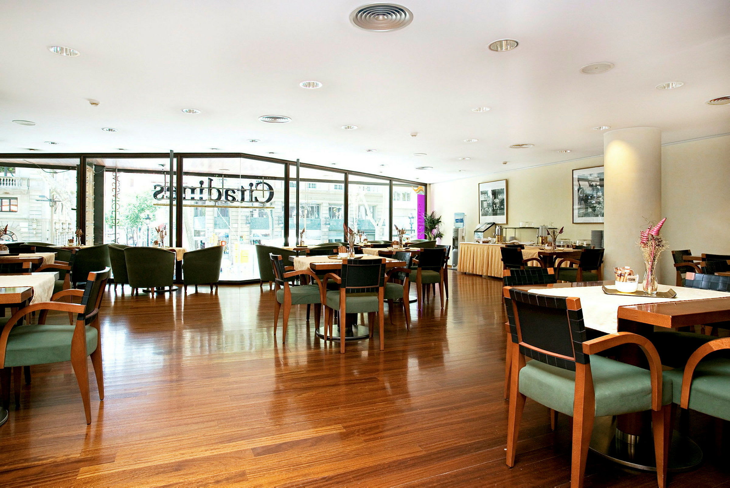 En inomhusbild av en elegant restaurang med bord och stolar, där stora fönster släpper in dagsljus. (AI-genererad text)