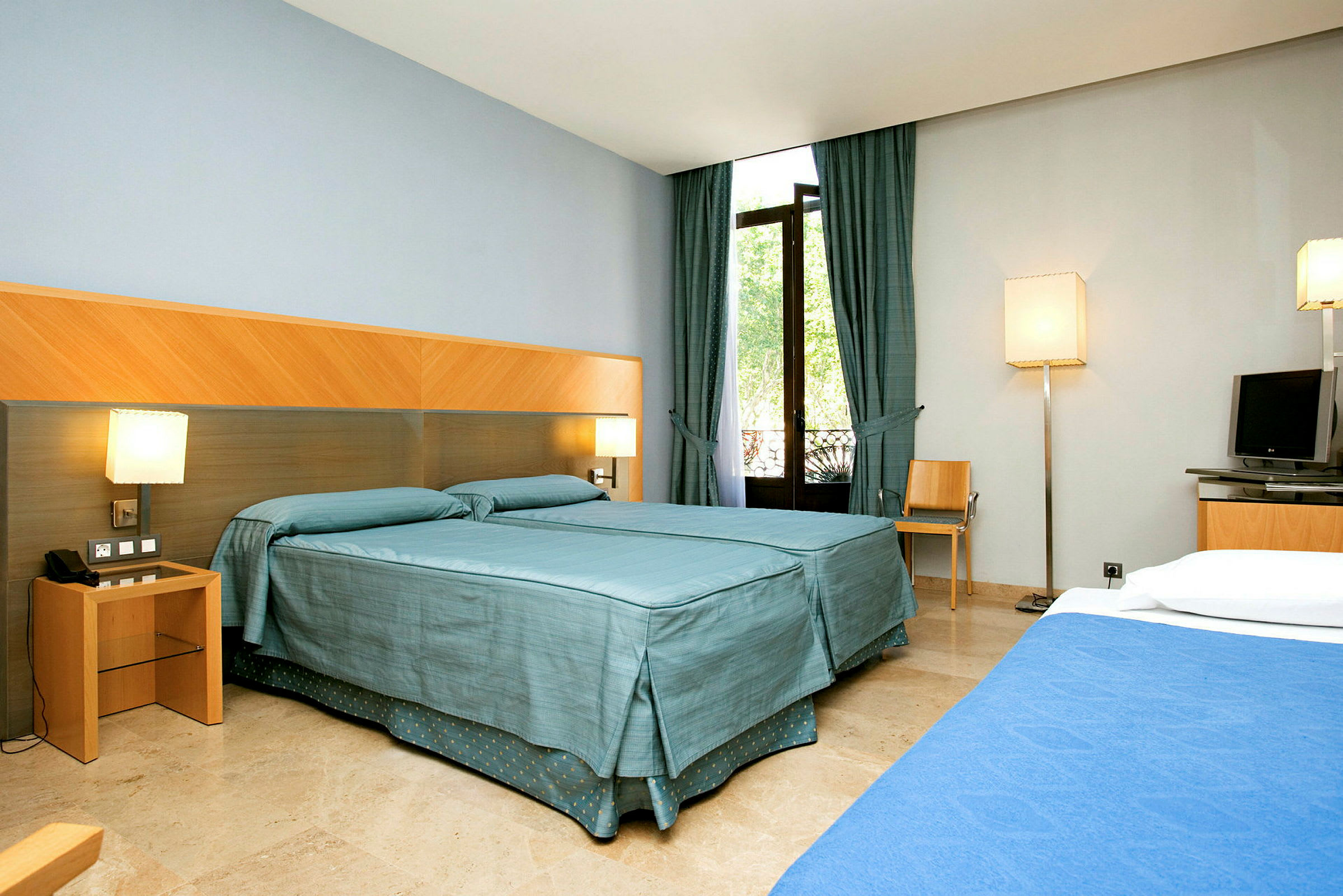 Hotellrum med två bäddar, gardiner och fönster. (AI-genererad text)