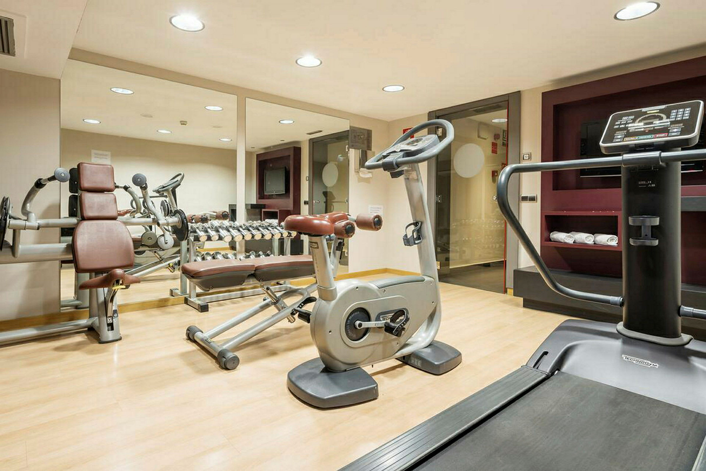Ett gym med träningsutrustning som löpband, motionscykel och fria vikter. (AI-genererad text)